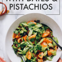 Hand holding a bowl of vegan and gluten-free vibrant celery salad with dates and pistachios