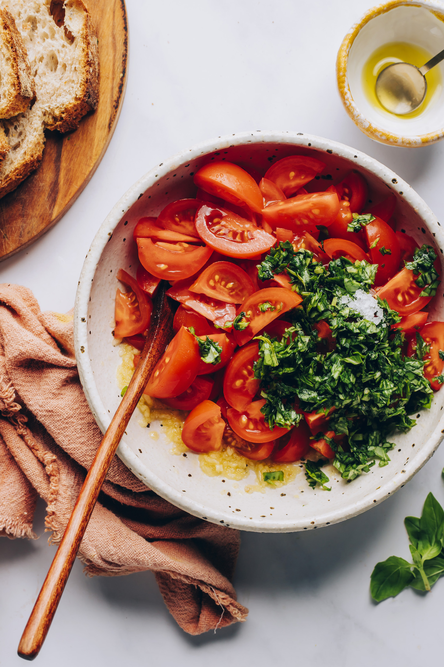 Bowl of sliced cherry tomatoes, basil, salt, olive oil, and garlic