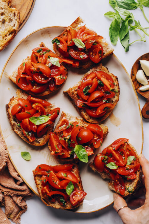 Picking up a slice of cherry tomato bruschetta