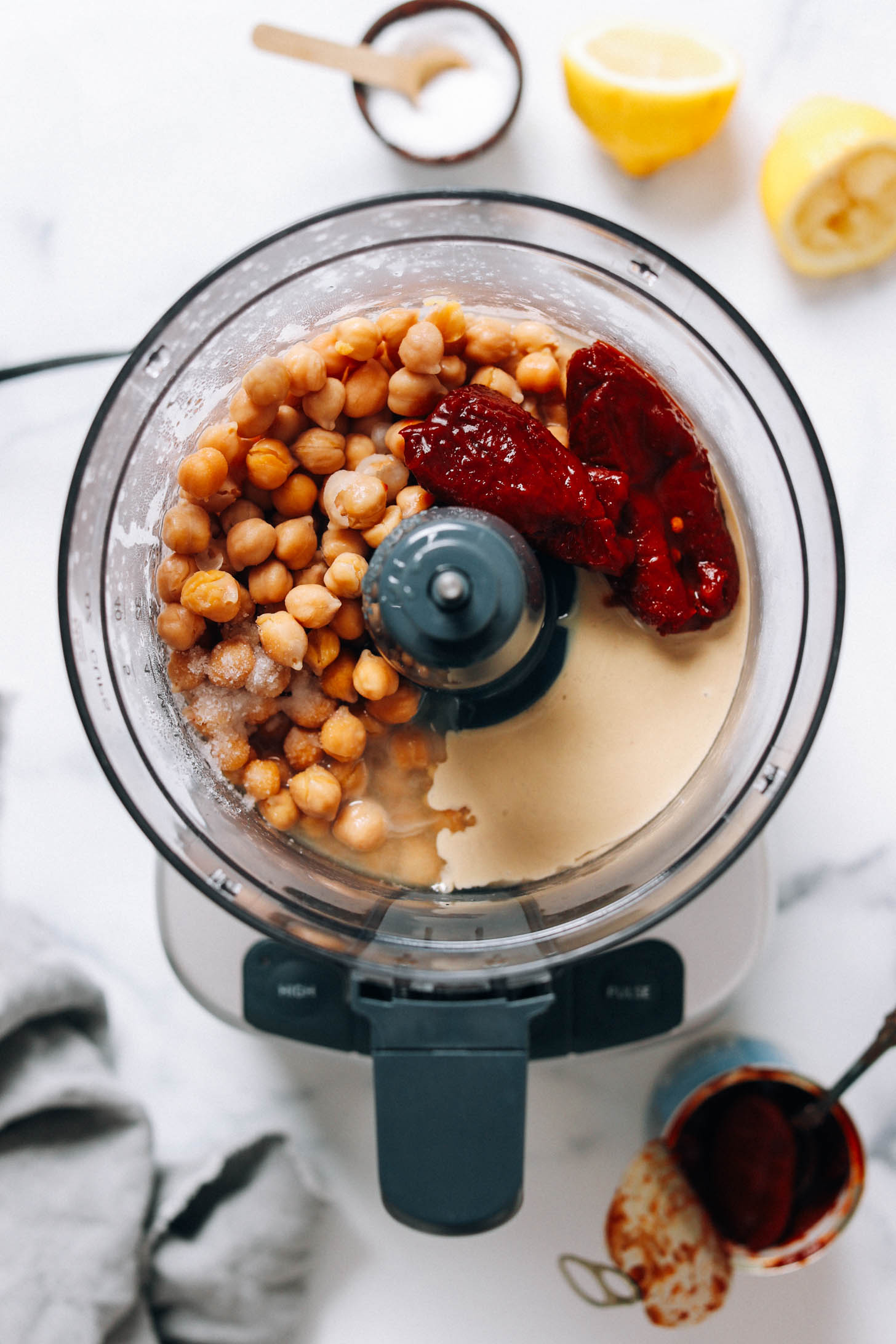 Food processor with chickpeas, chipotle peppers, salt, lemon juice, and tahini