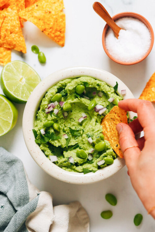 Dipping a tortilla chip into a dish of edamame guacamole