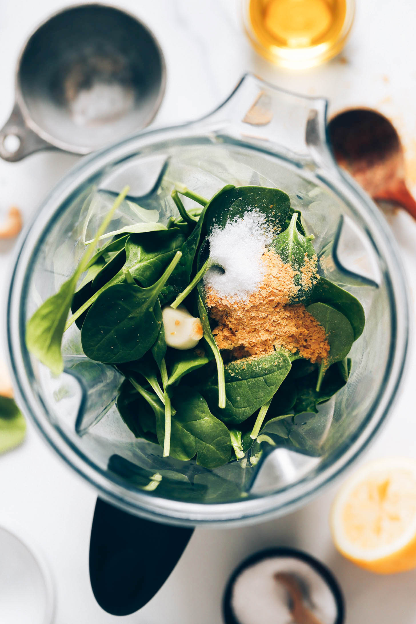 Blender with spinach, basil, garlic, nutritional yeast, salt, cashews, and water