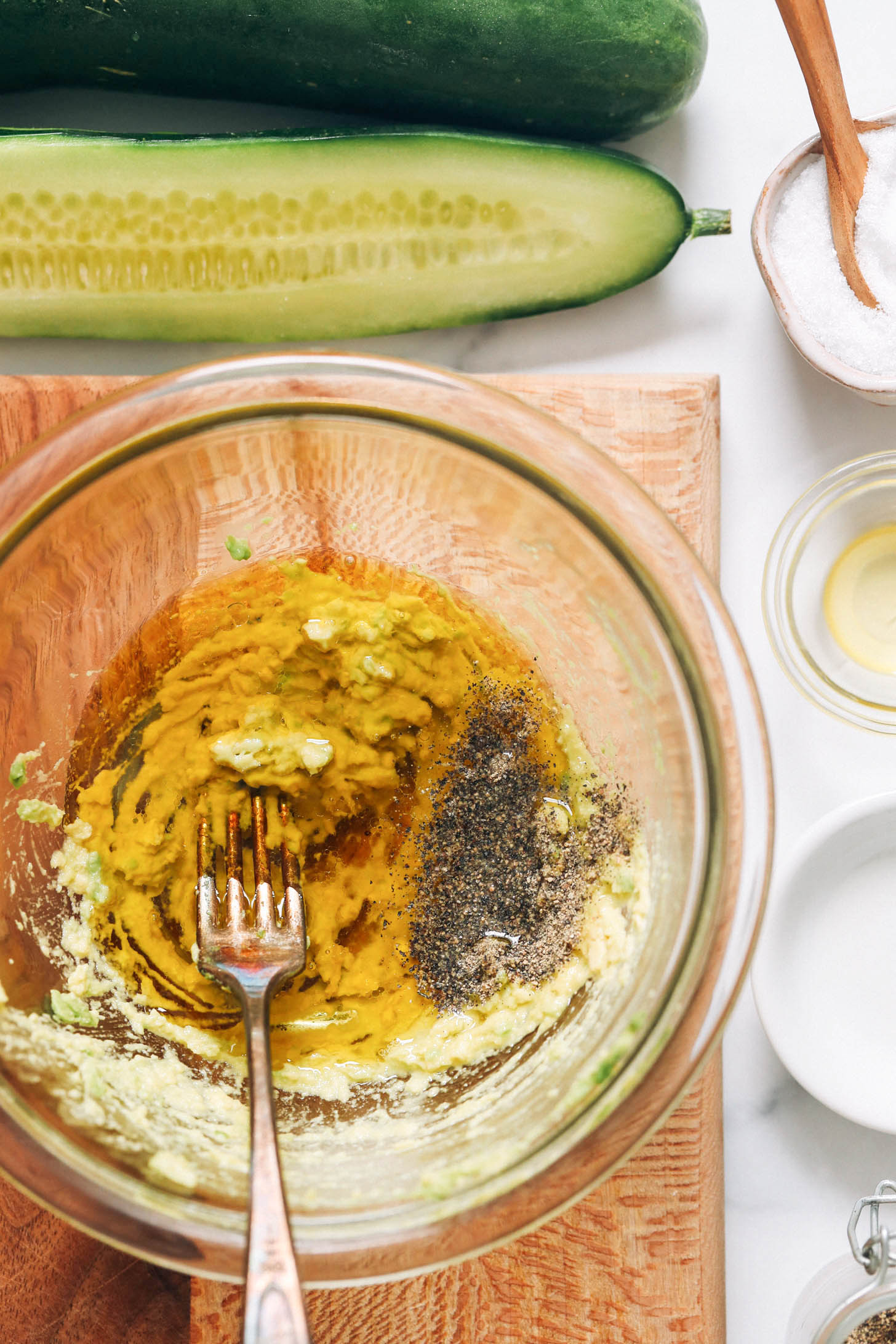 Fork in a bowl of mashed avocado, olive oil, white balsamic vinegar, salt, and pepper