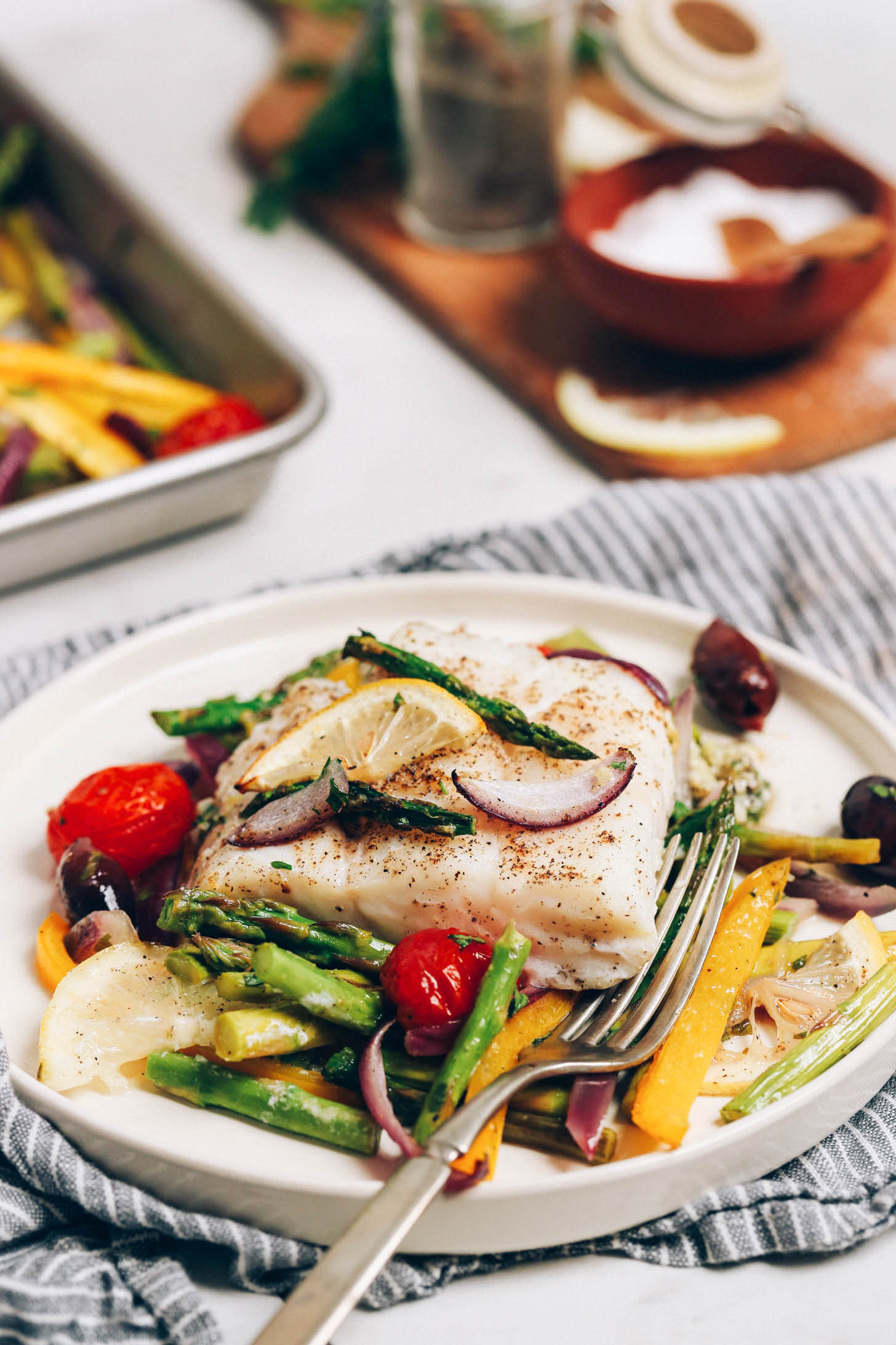 Plate with a baked cod fillet and spring vegetables