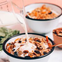 Pouring dairy-free milk into a bowl of Carrot Cake Oatmeal made in the Instant Pot