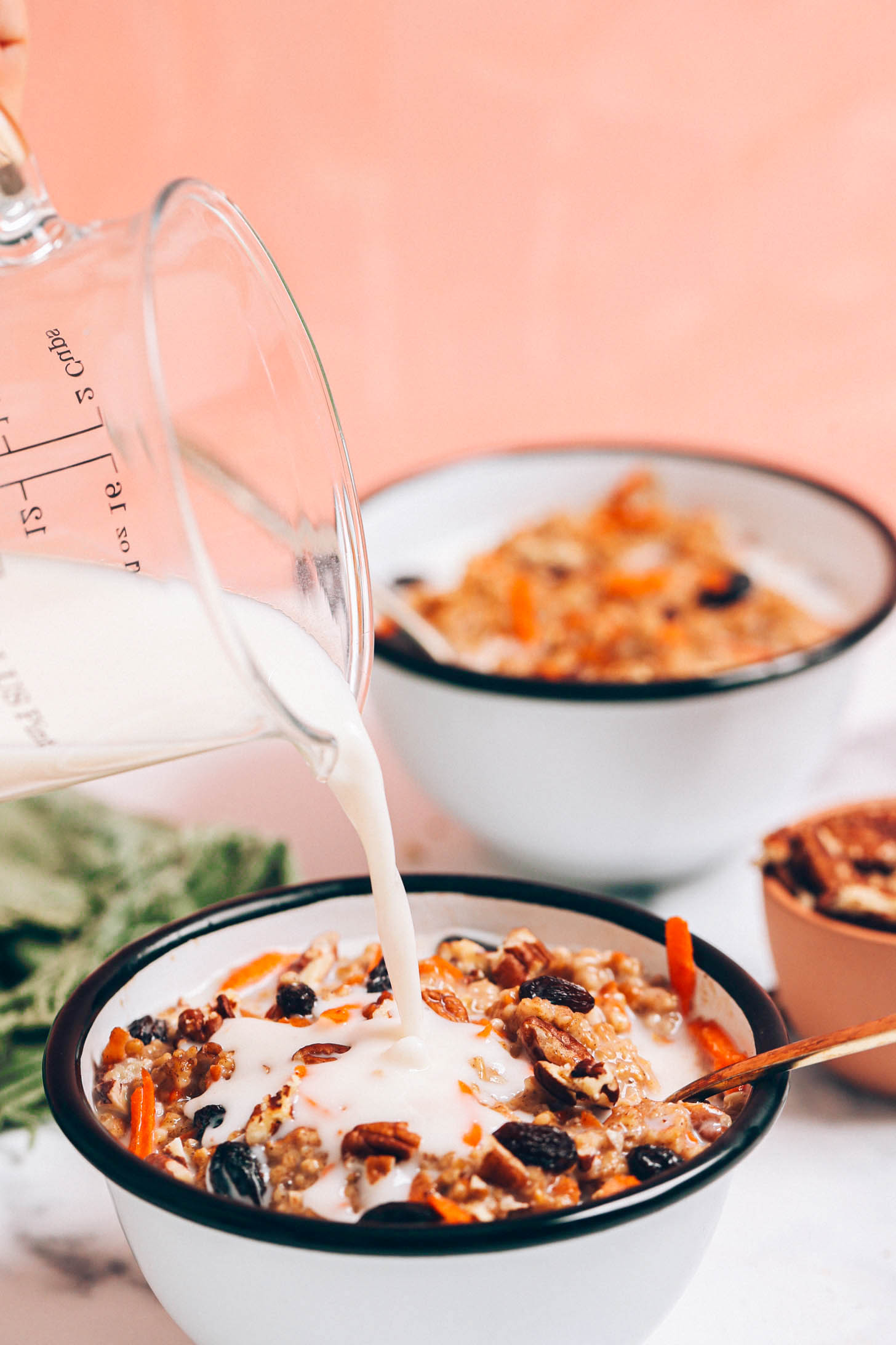 Pouring dairy-free milk into a bowl of carrot cake steel cut oats