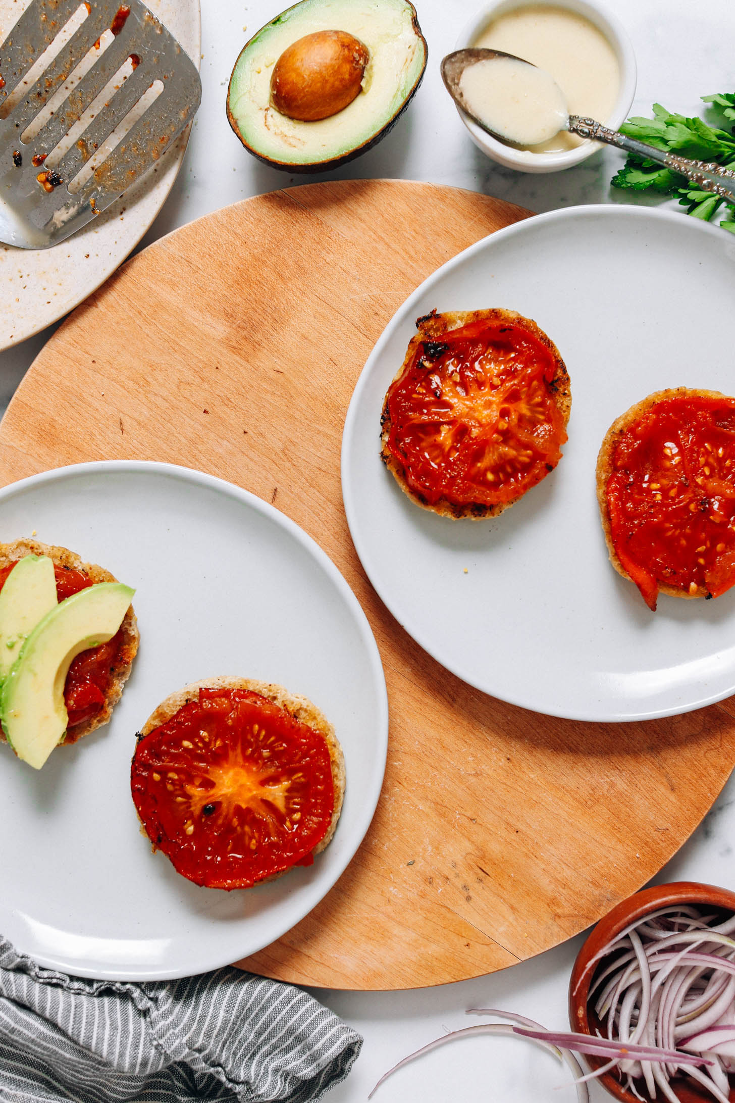 Two plates with English muffins topped with seared tomato slices