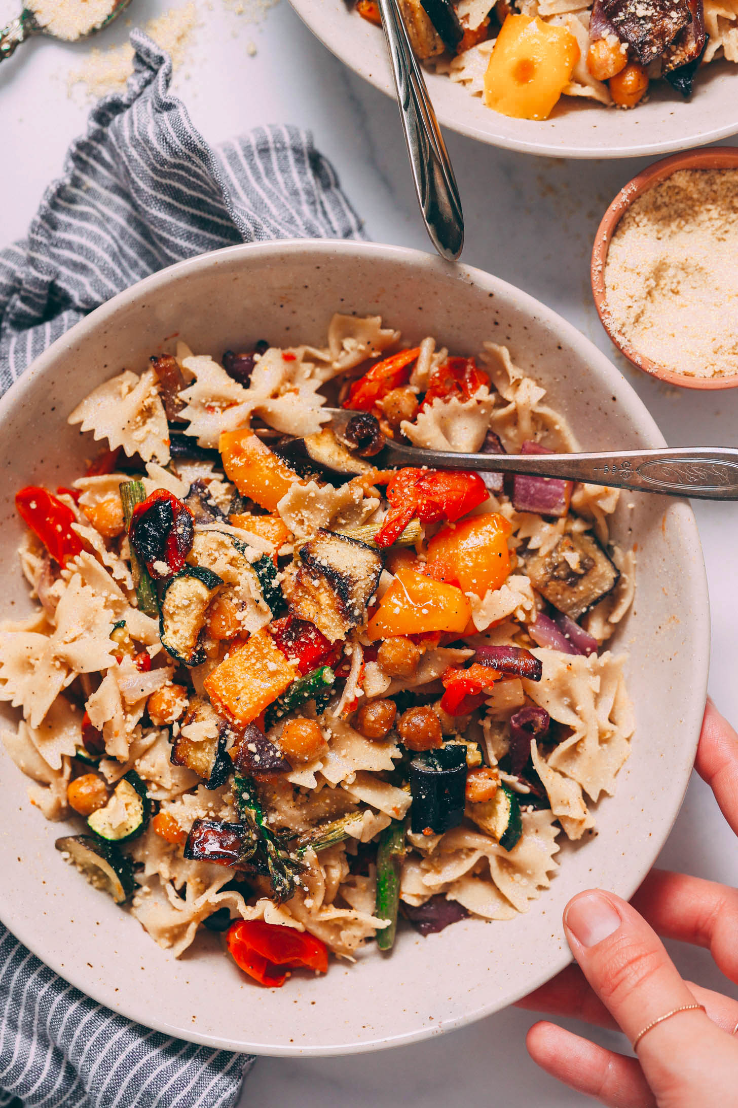 Vegan parmesan cheese sprinkled over a bowl of pasta primavera