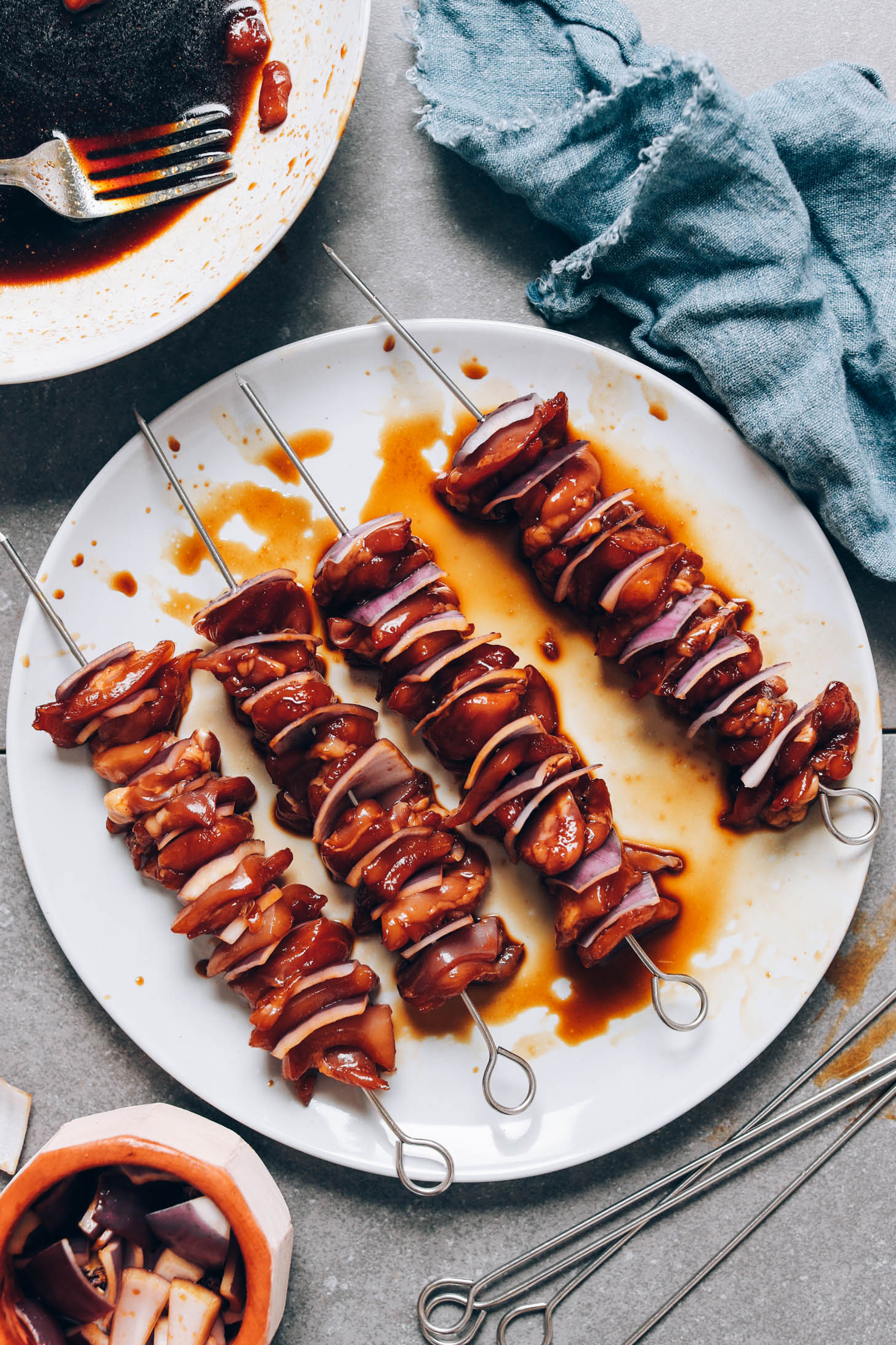 Teriyaki chicken and red onion on metal skewers