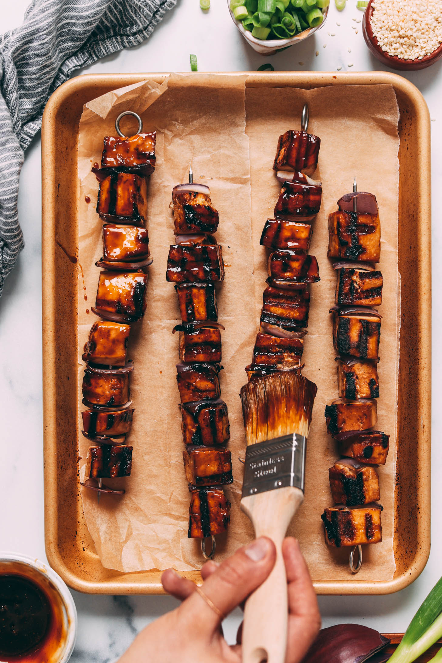 Brushing a teriyaki glaze onto grilled tofu skewers