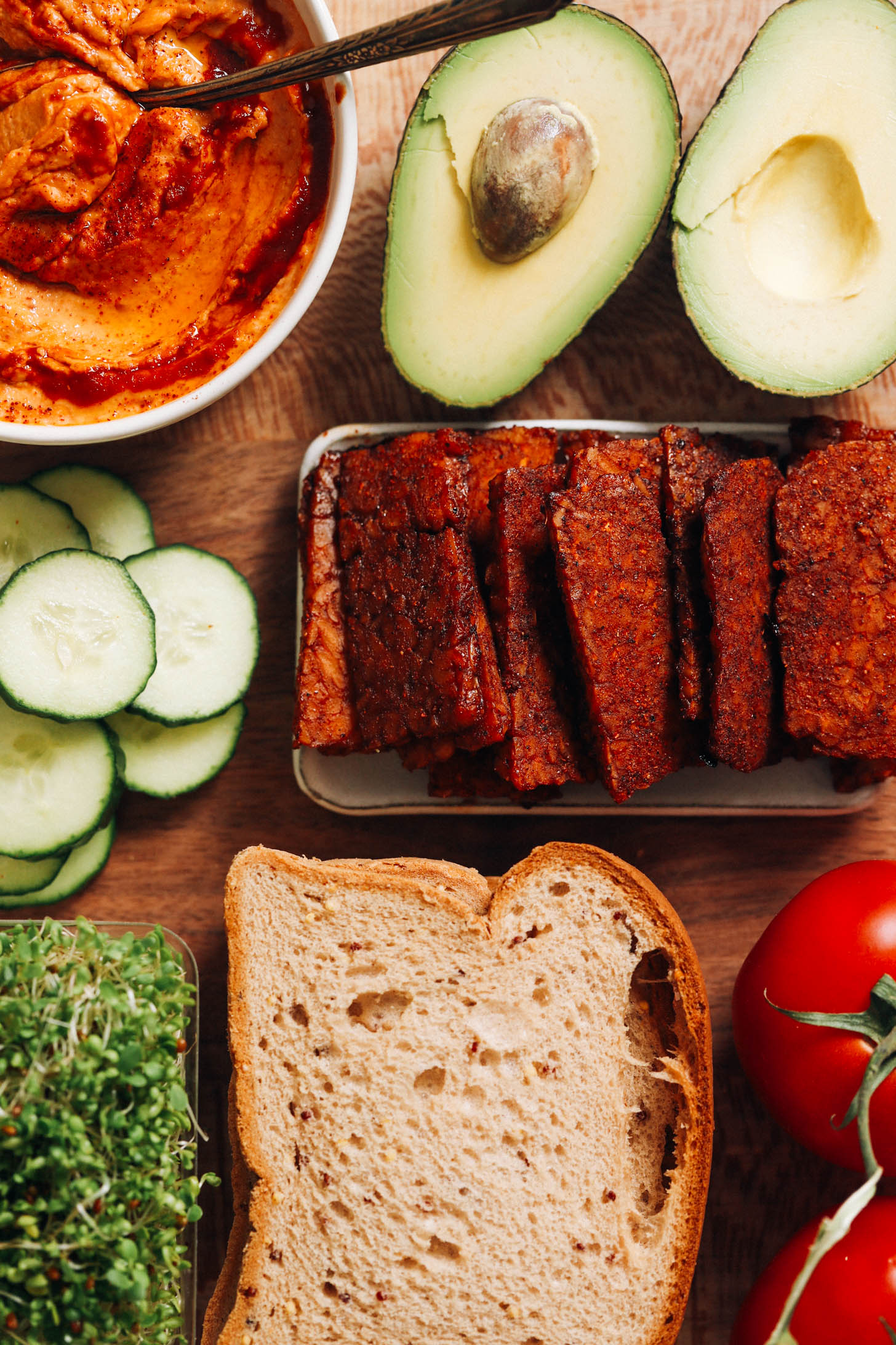 Tempeh bacon, tomatoes, bread, sprouts, cucumber, hummus, and avocado