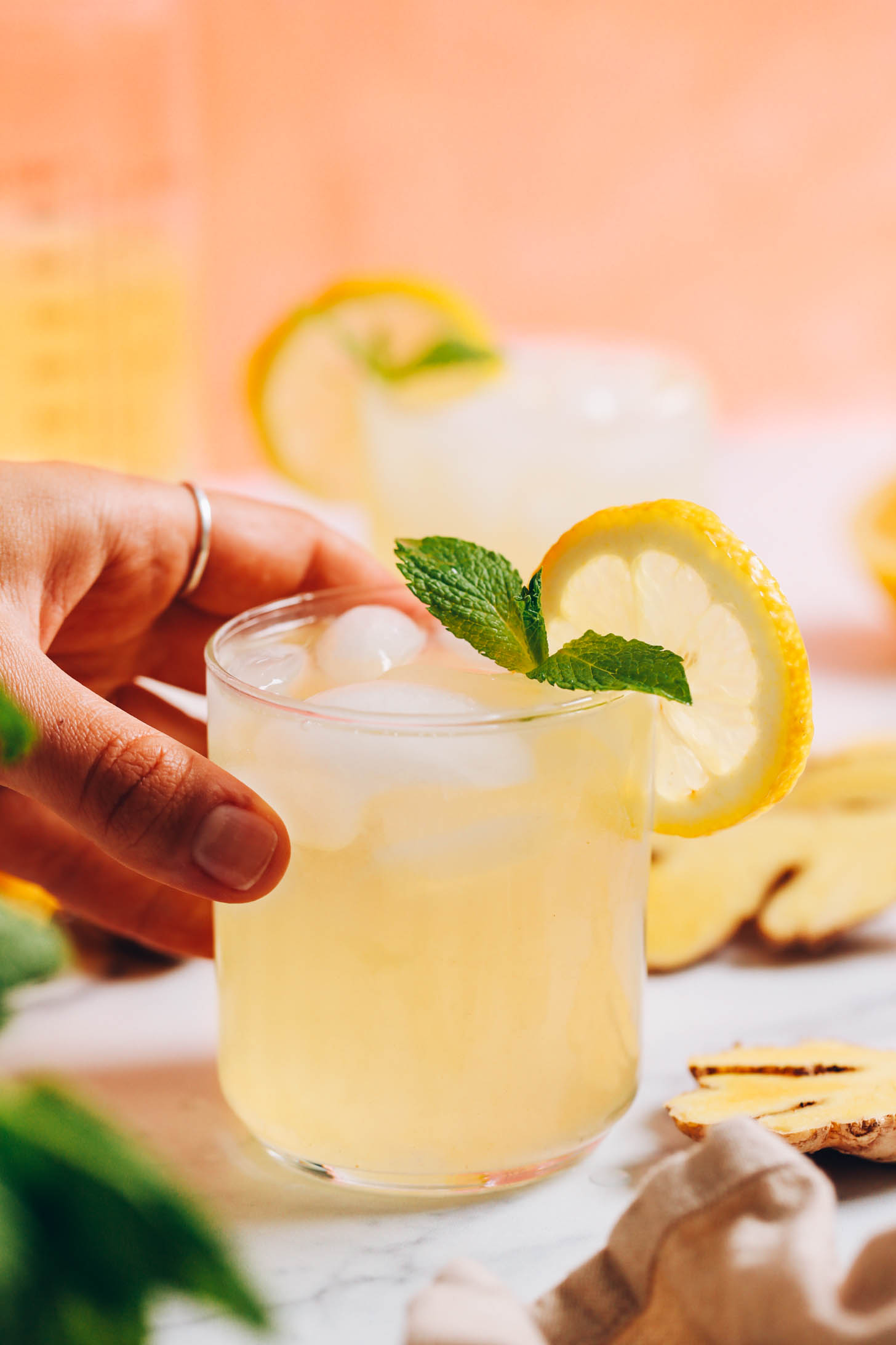 Hand reaching in to pick up a glass of ginger lemonade