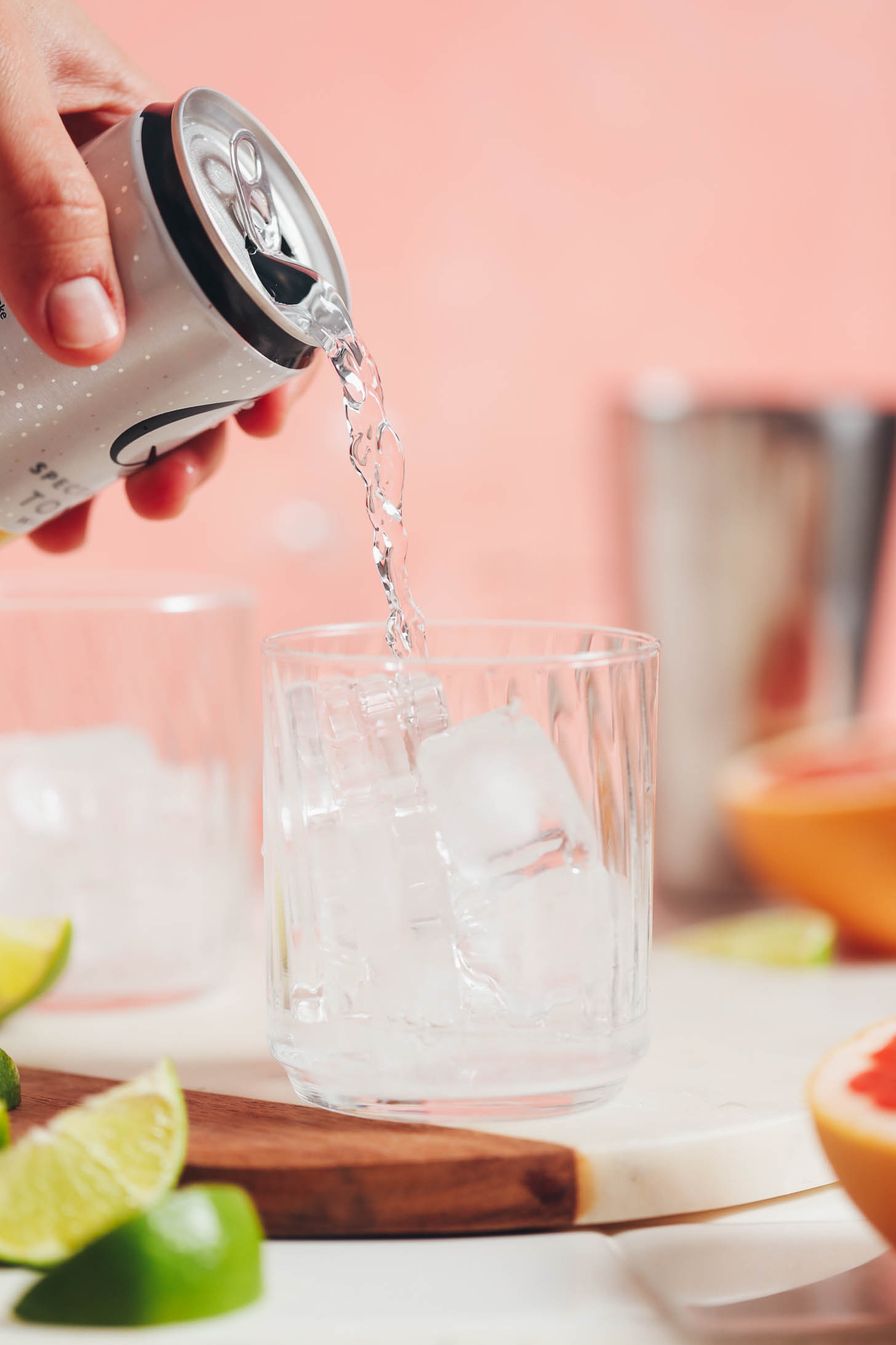 Pouring sparkling water into a glass of ice cubes