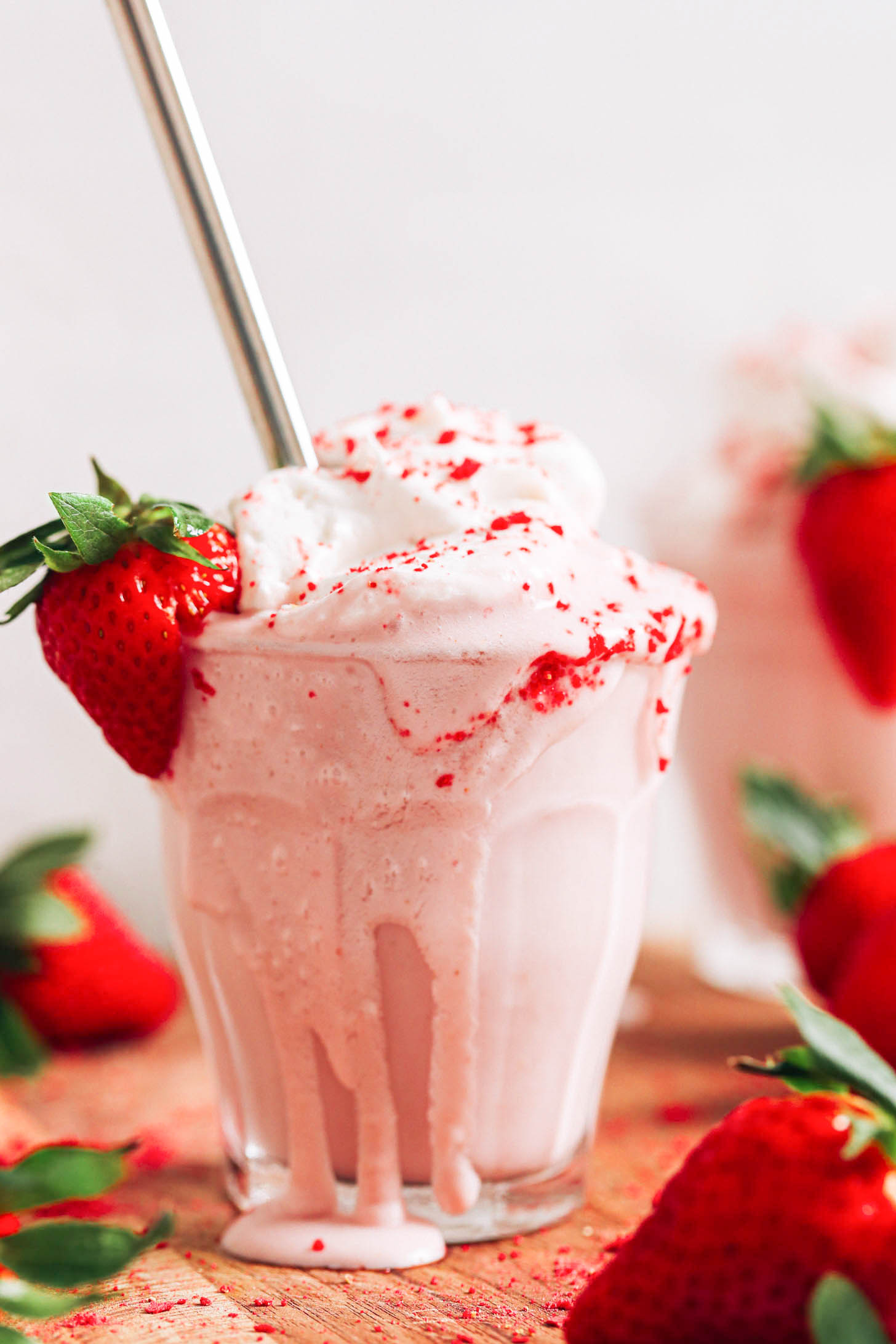 Overflowing glass of our strawberry milkshake recipe
