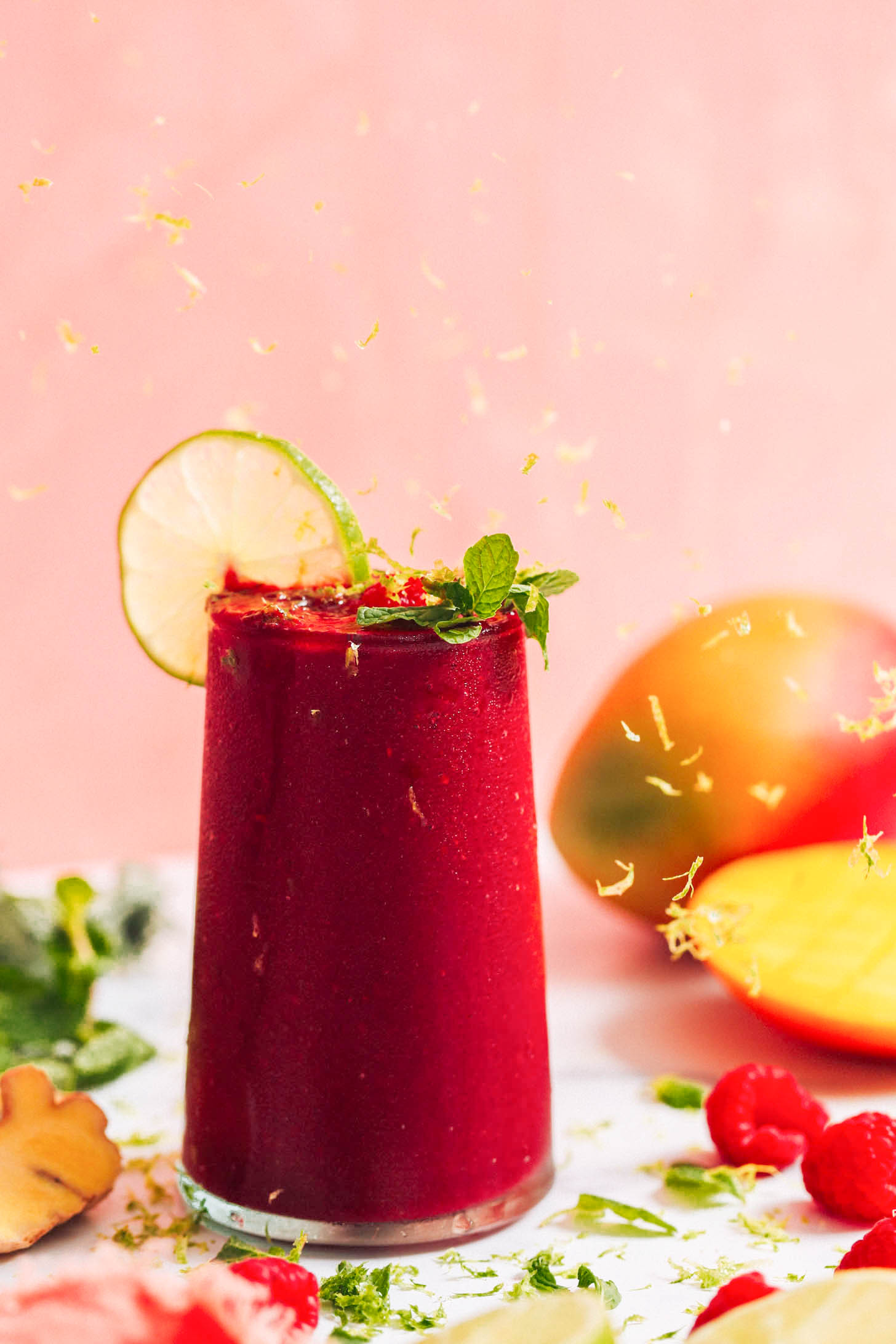 Lime zest falling onto a glass of our mango beet smoothie recipe