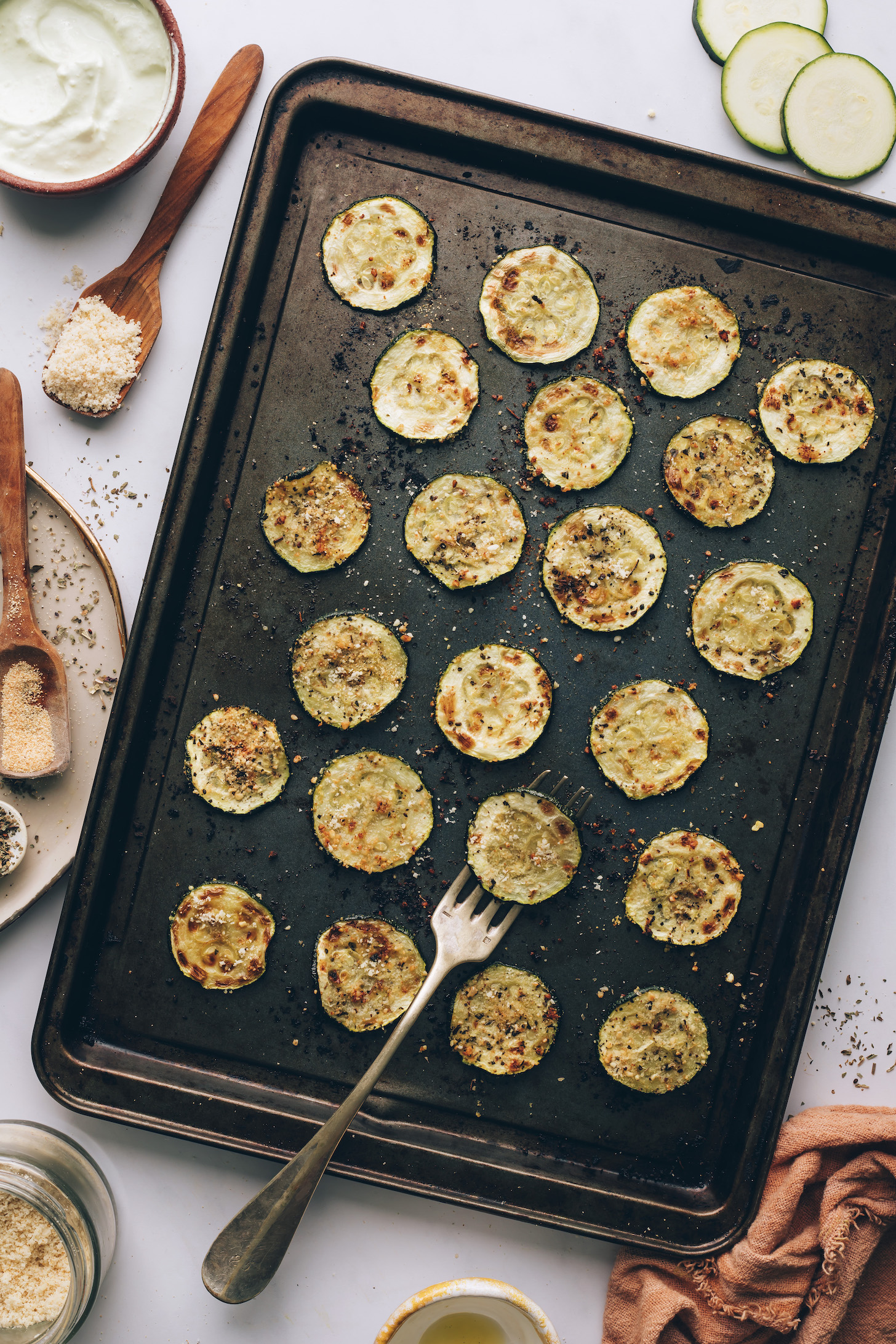 Golden brown zucchini slice on a fork on a baking sheet