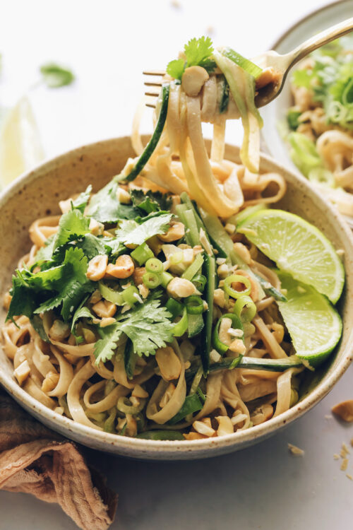 Swirling cold sesame noodle salad on a fork above a bowl