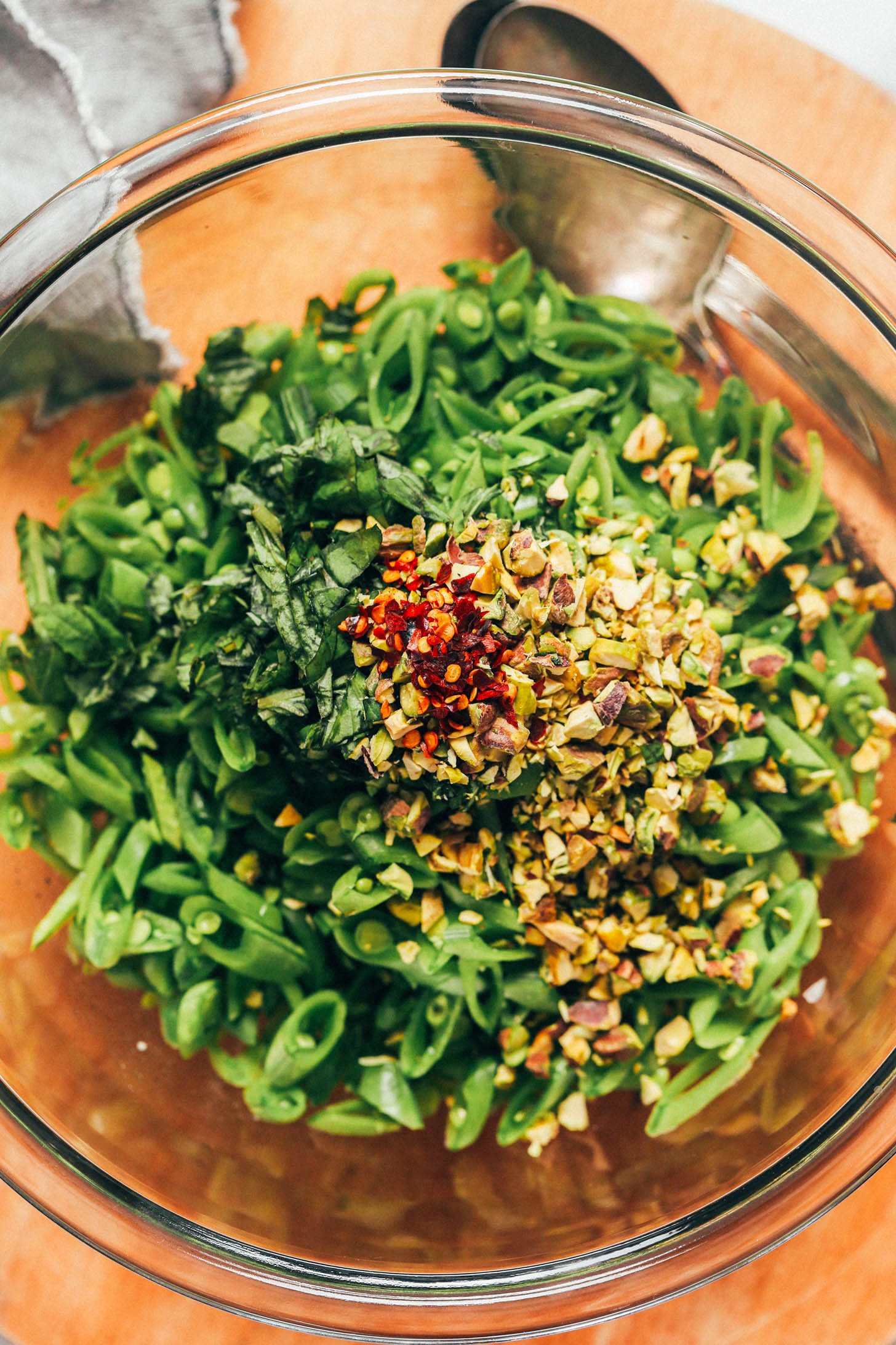 Sliced snap peas topped with chopped basil, pistachios, and red pepper flakes