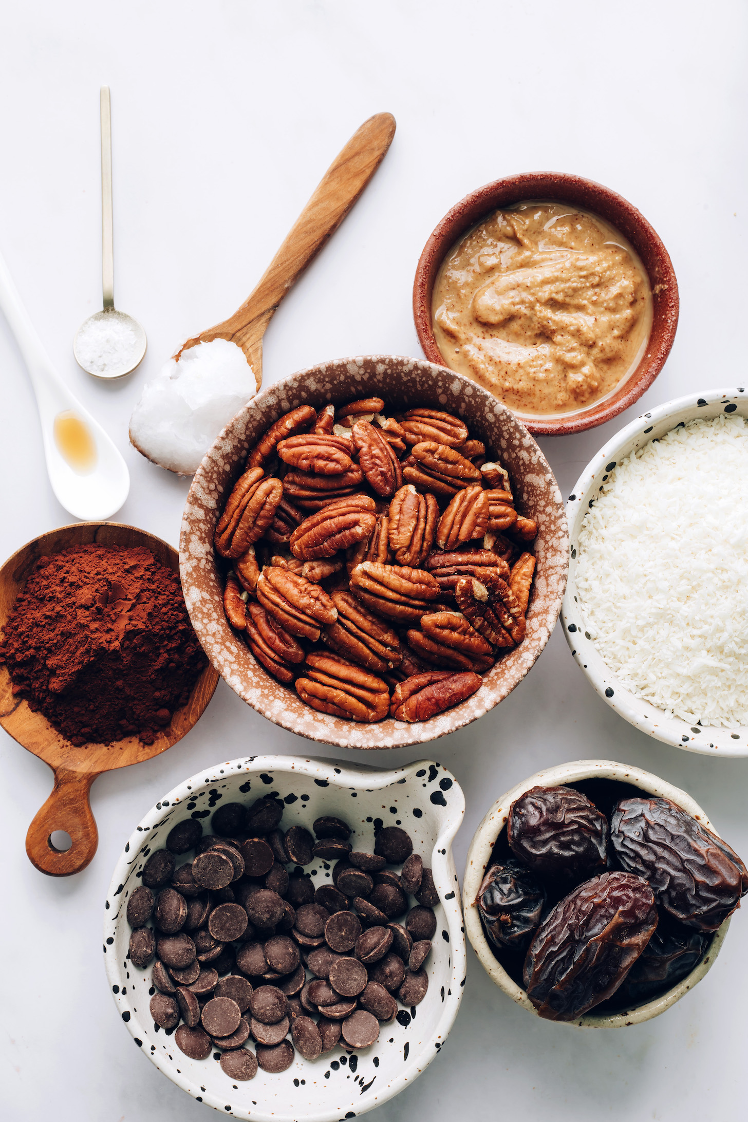 Vanilla, salt, coconut oil, almond butter, cacao powder, pecans, coconut, dates, and chocolate chips