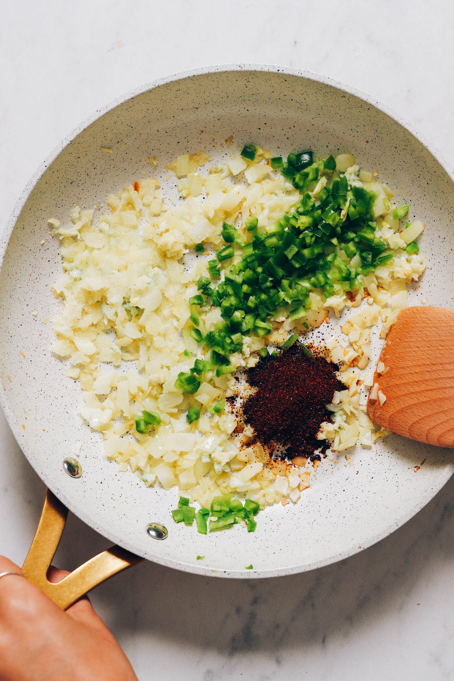 Sautéing onion, garlic, serrano, and chili powder in a skillet