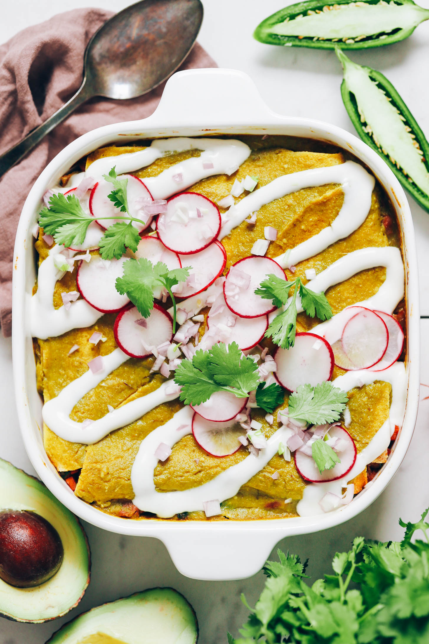 Vegan sour cream, shallot, radish, and cilantro over a green enchilada casserole