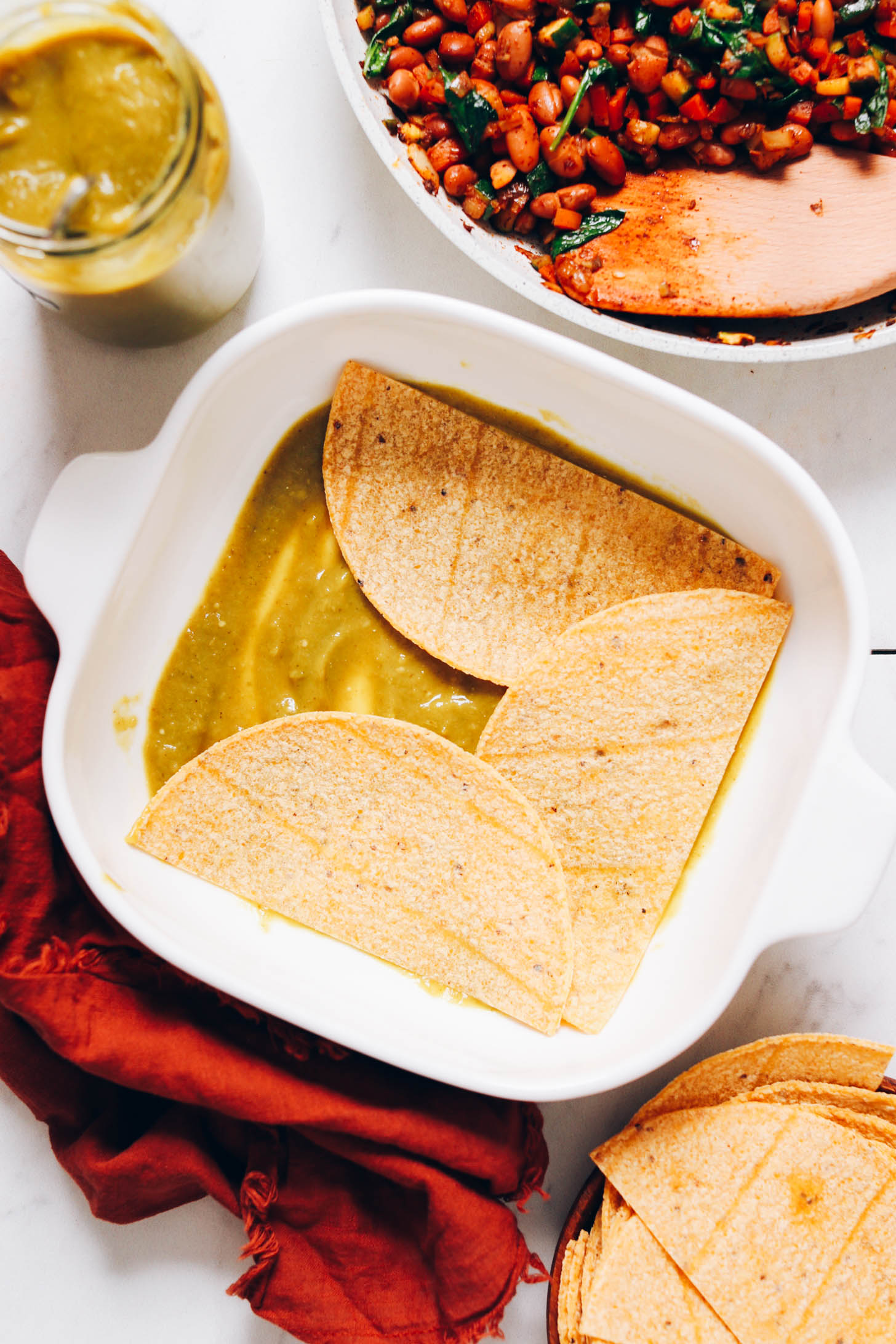 Baking pan with tortillas over green enchilada sauce