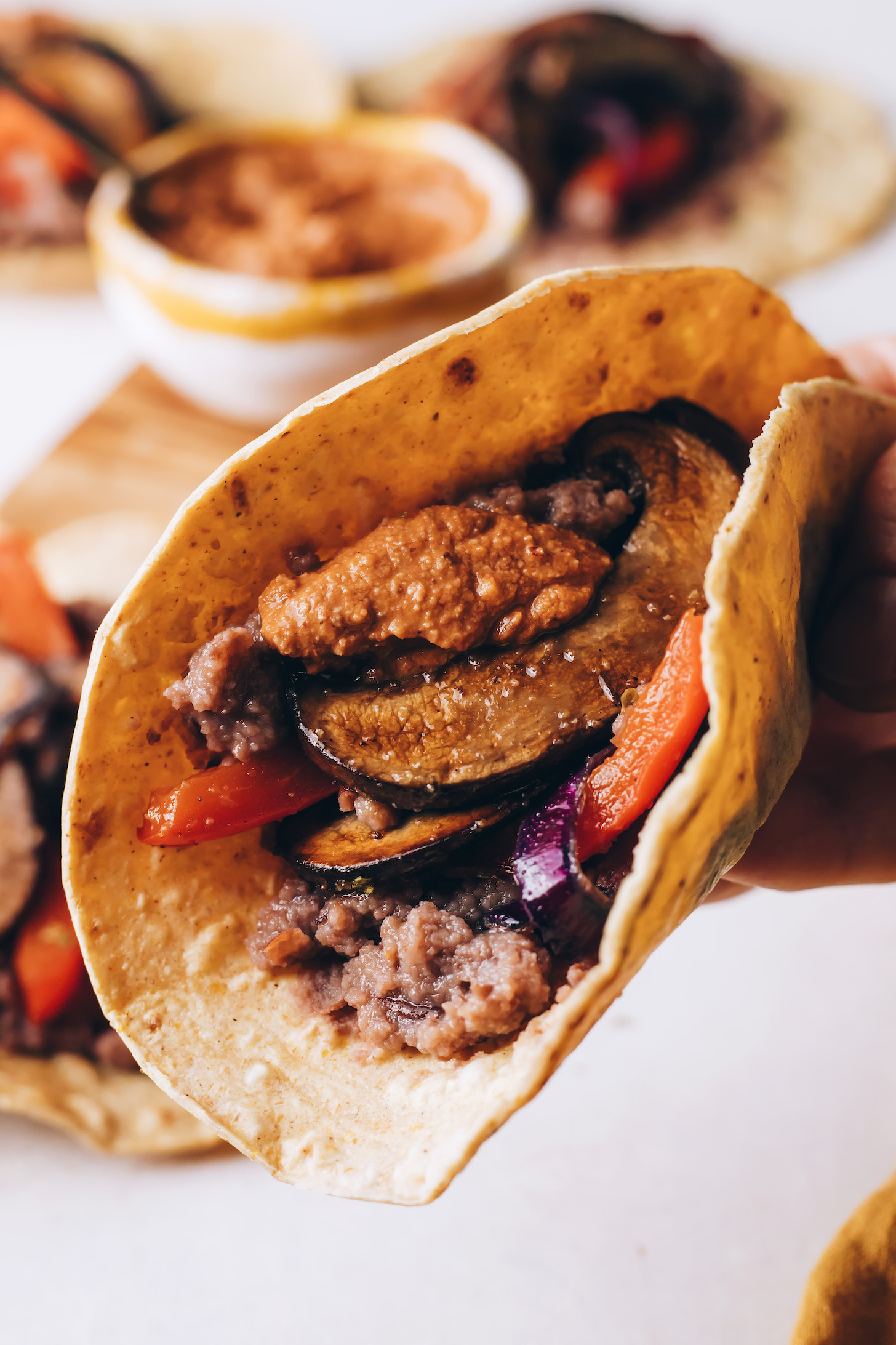 Close up shot of a taco with refried beans, fajitas, and chipotle pecan pesto