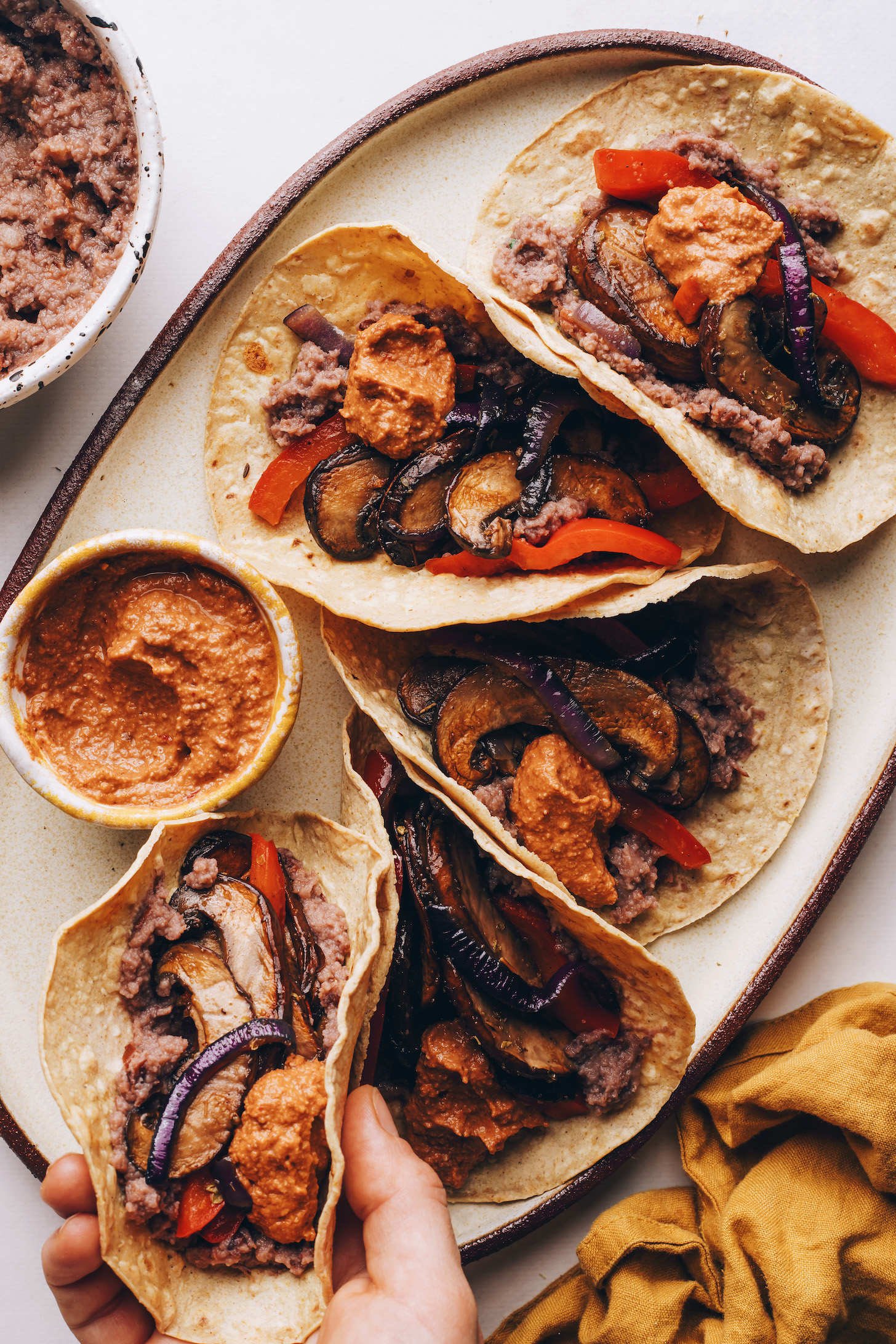 Hand reaching in to pick up a vegan taco from a platter