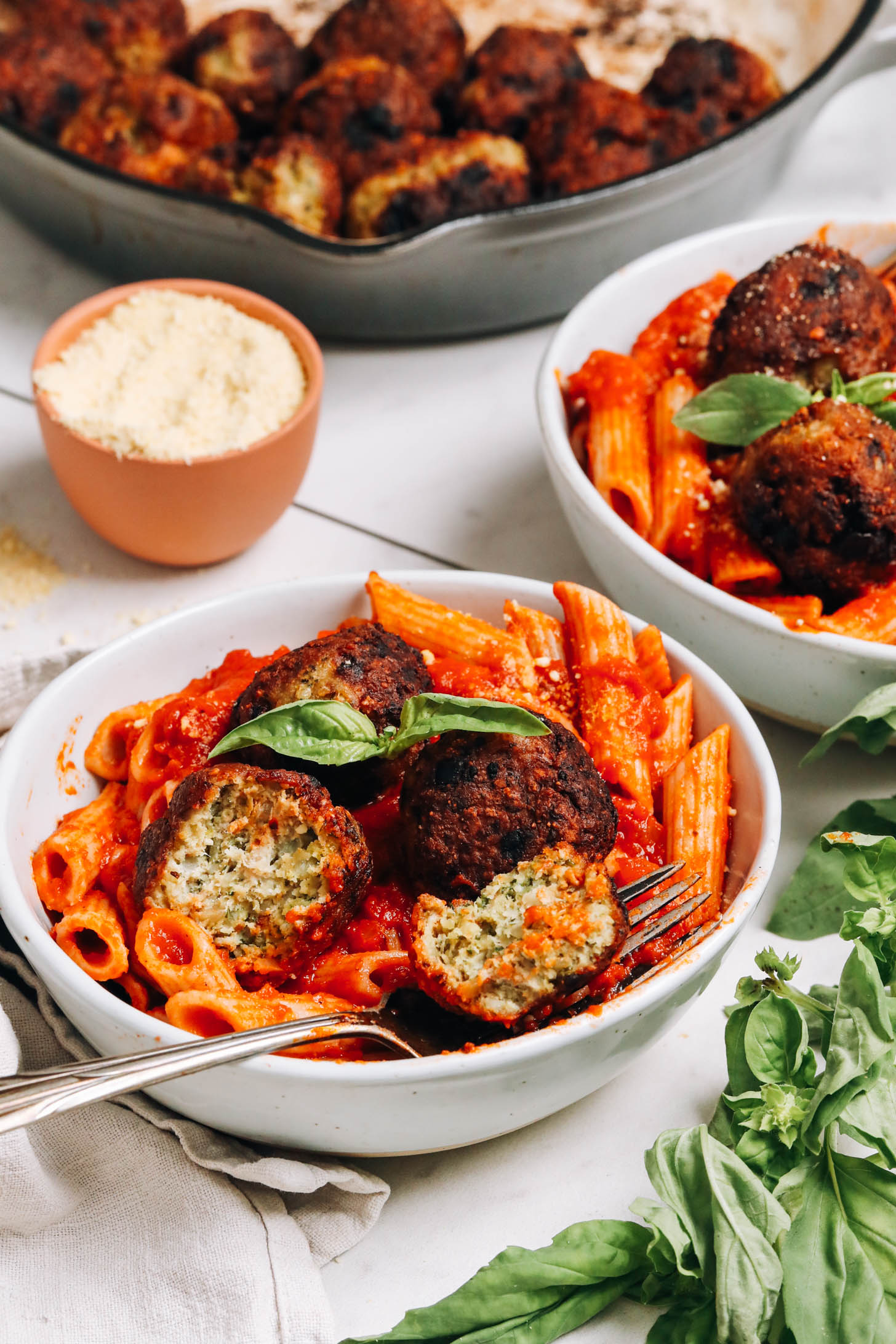 Skillet and bowls of turkey meatballs over pasta