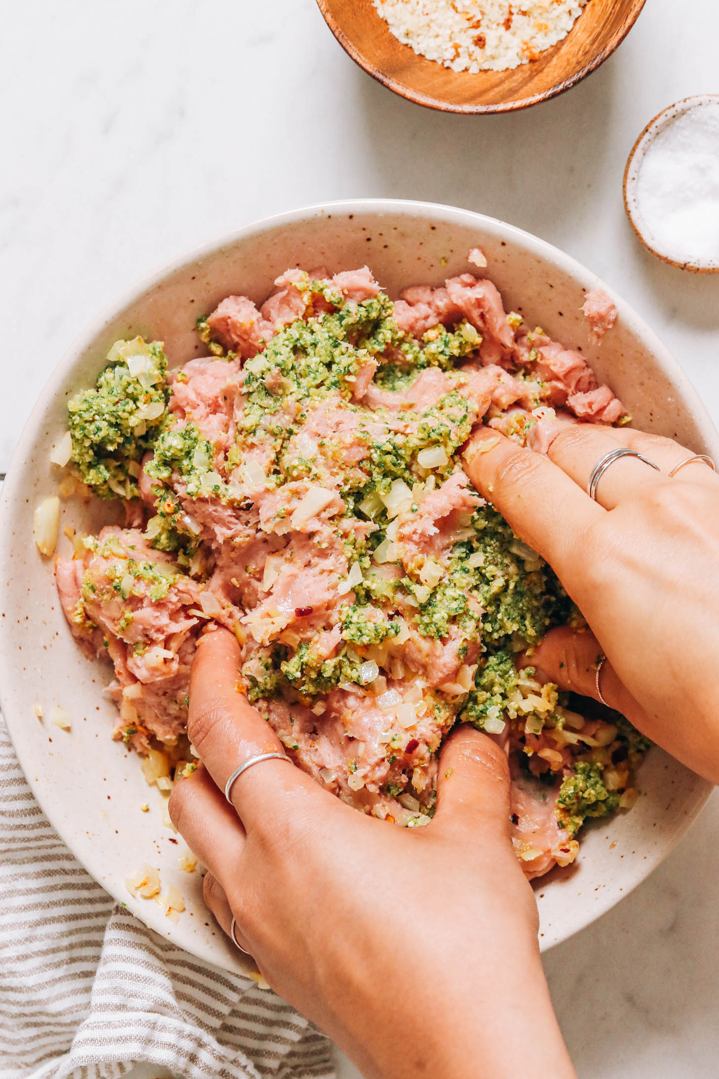 Mixing ground turkey with basil pesto and other seasonings