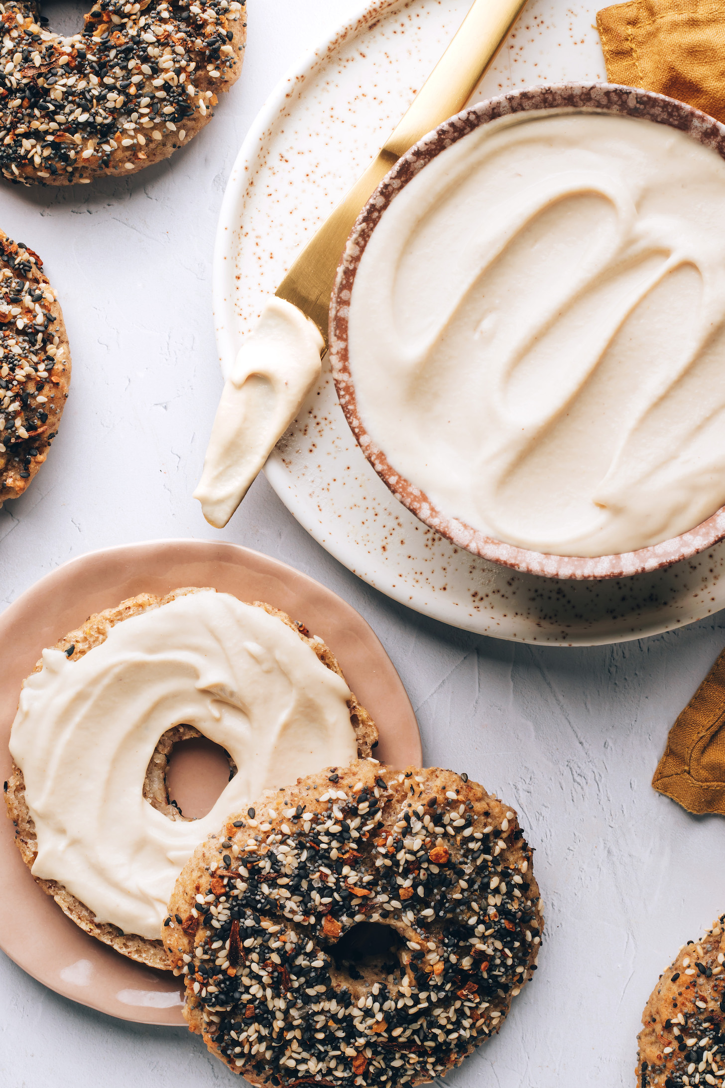 Knife and bowl of vegan cream cheese next to bagels