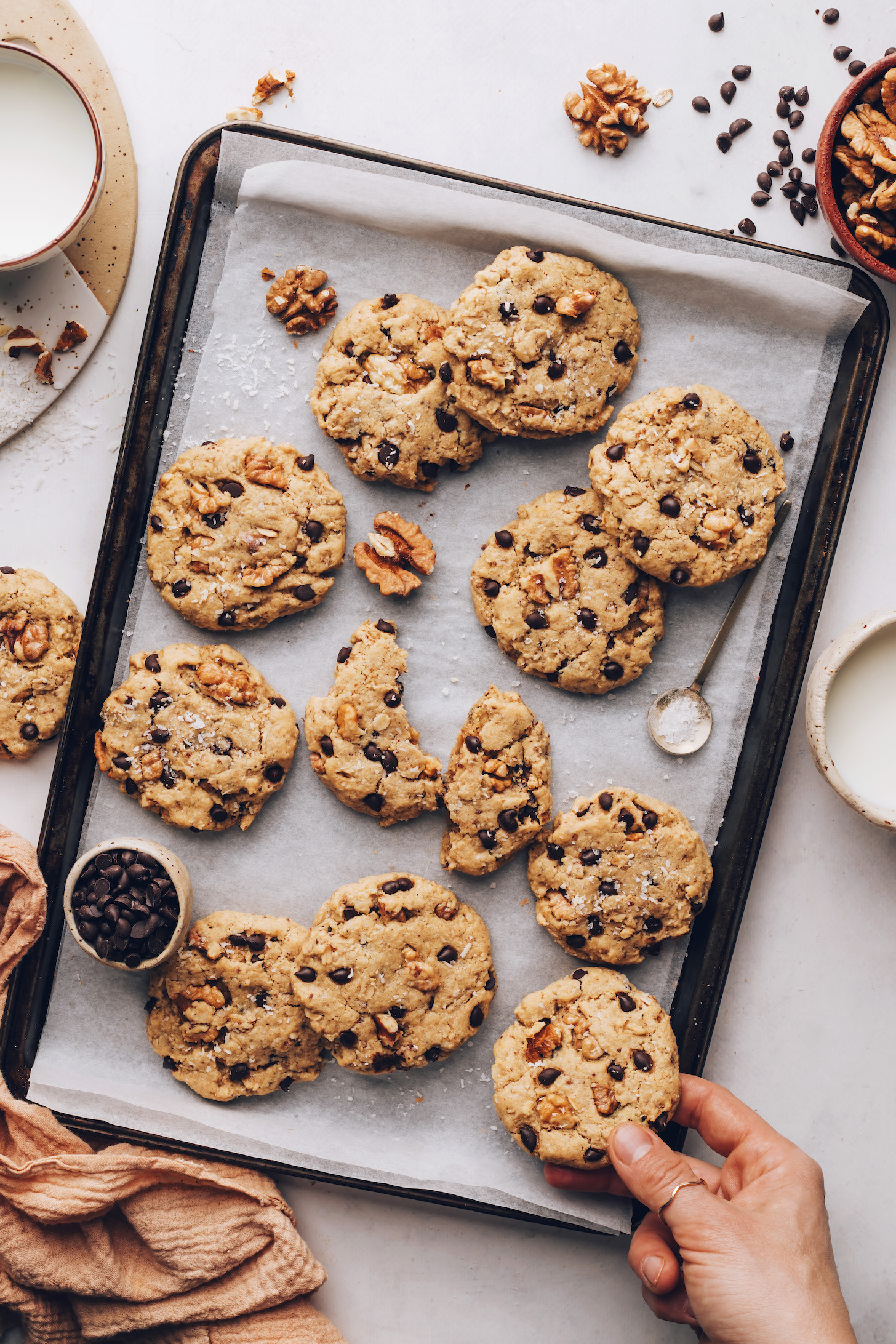 Hand reaching in to grab a cowboy cookie off a baking sheet