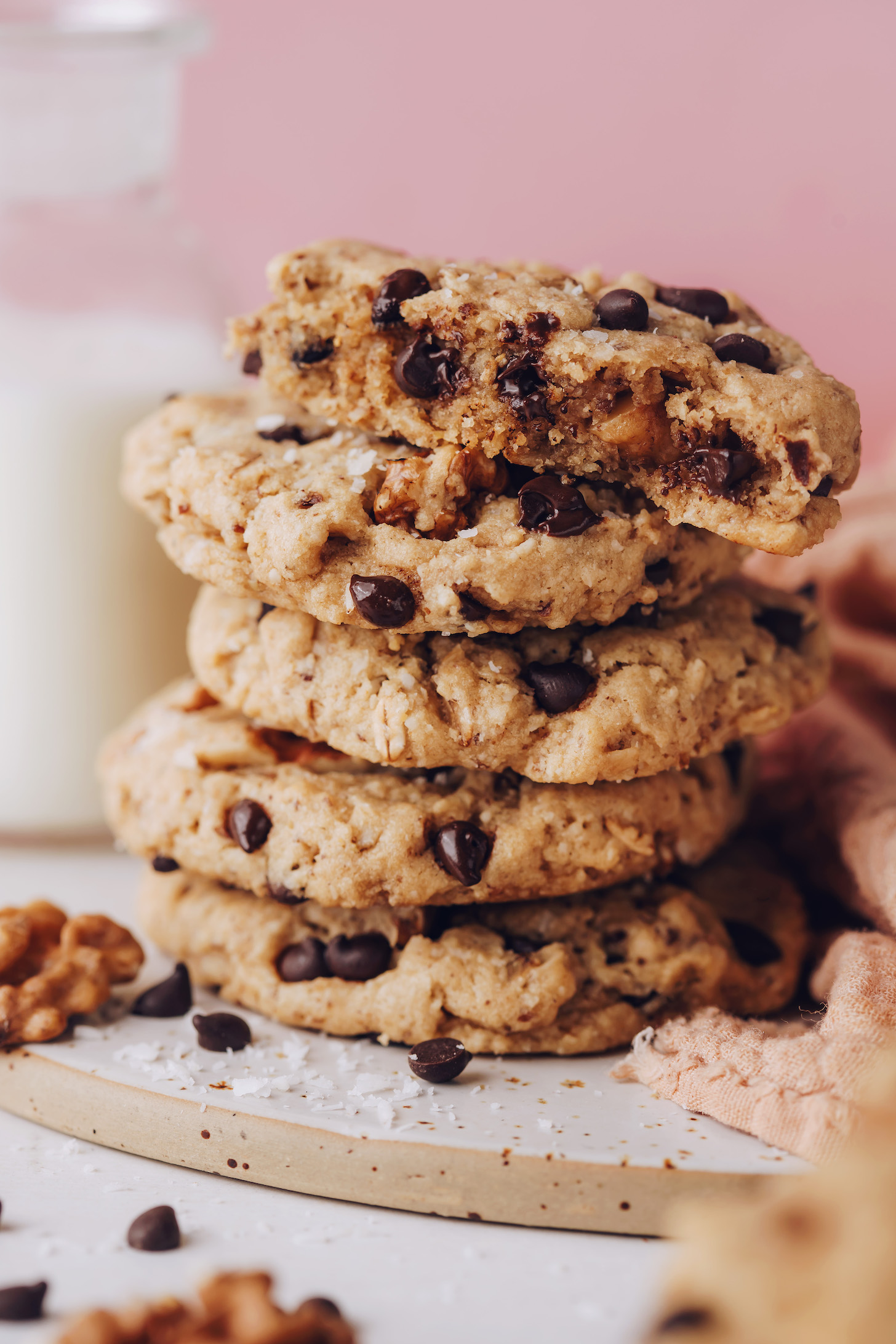 Half eaten cookie on a stack of oatmeal walnut oat chocolate chip cookies