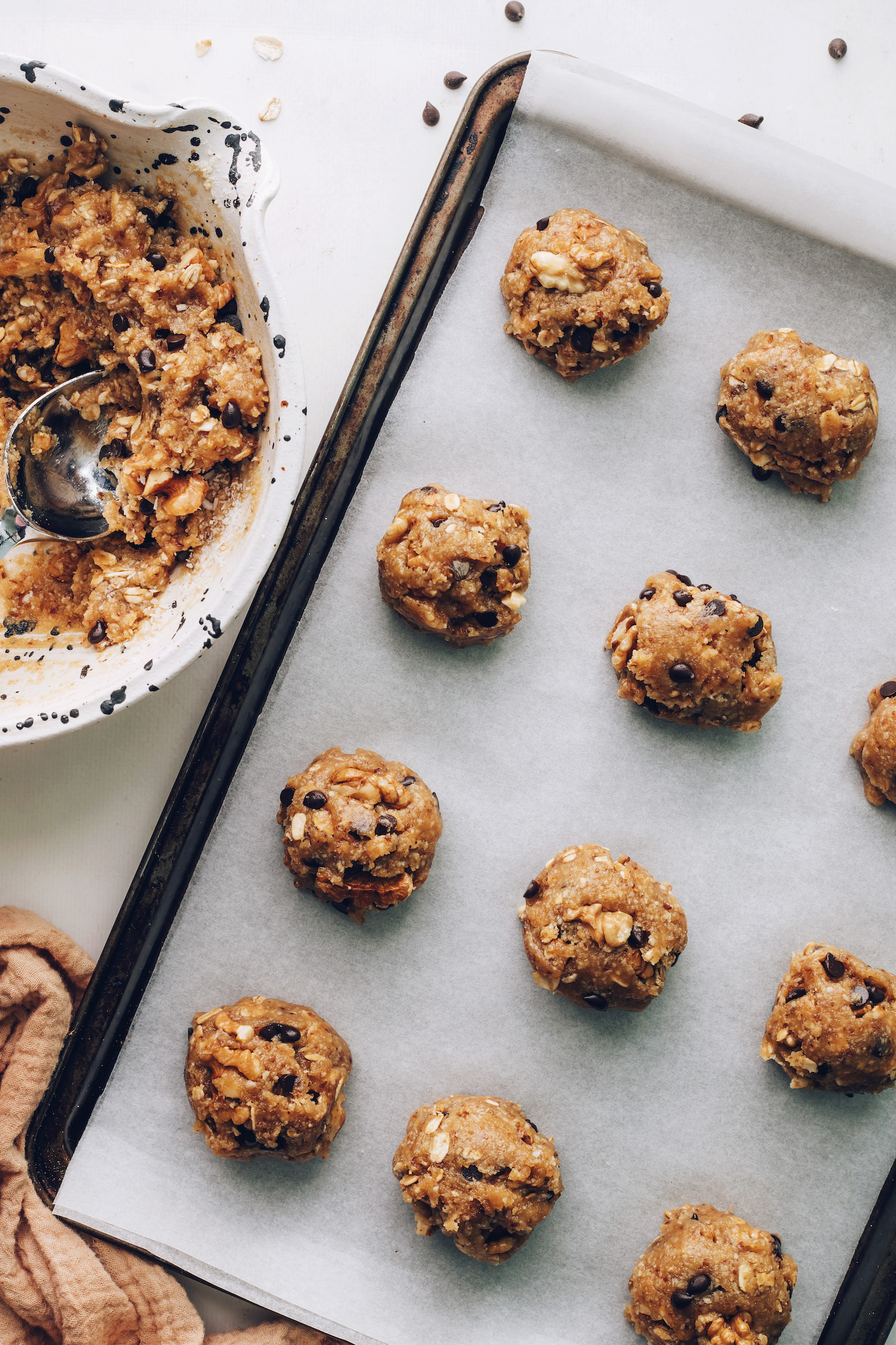 Bowl of cookie dough next to balls of dough on a baking sheet