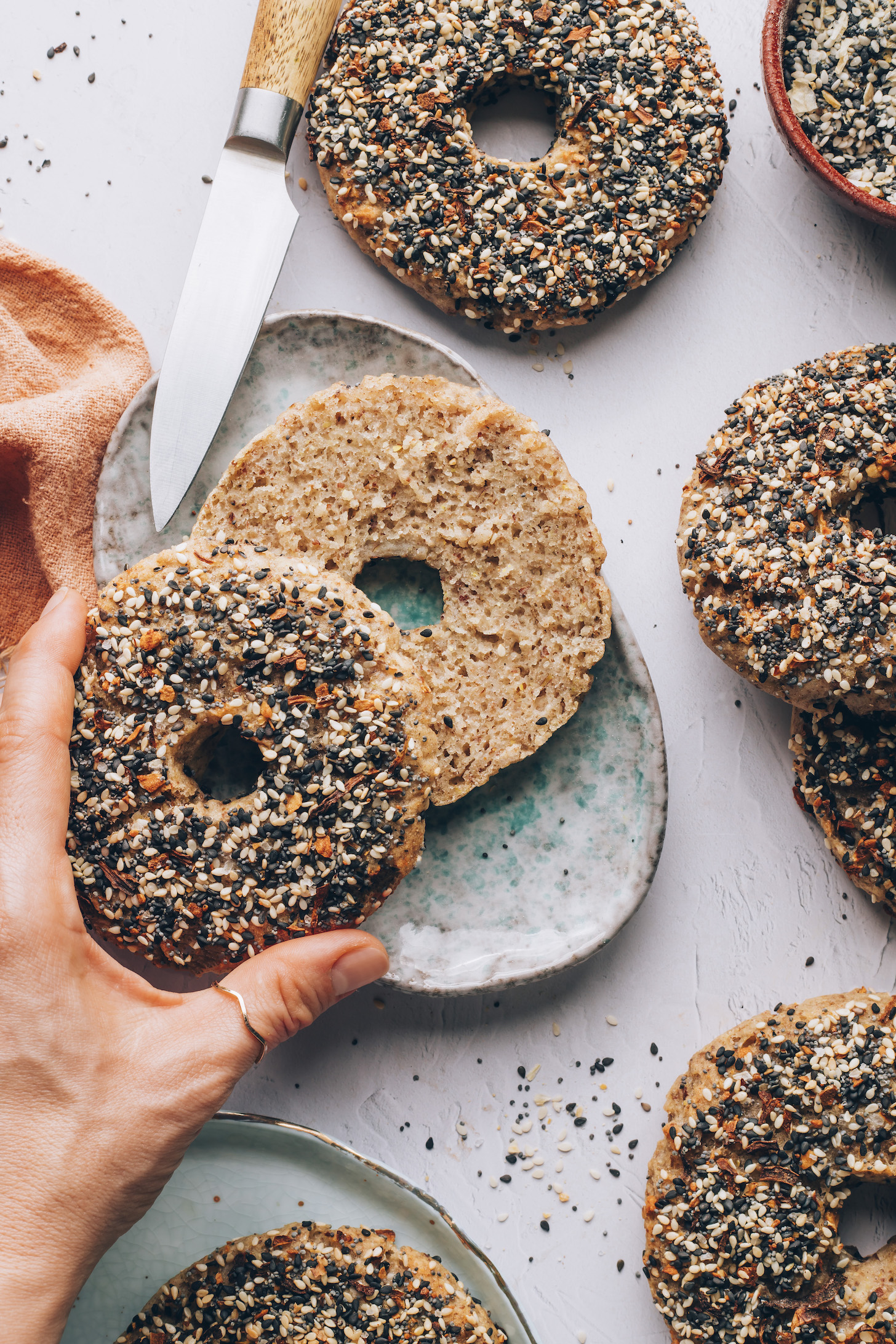 Picking up the top half of a gluten-free everything bagel to show the texture of the inside of a bagel