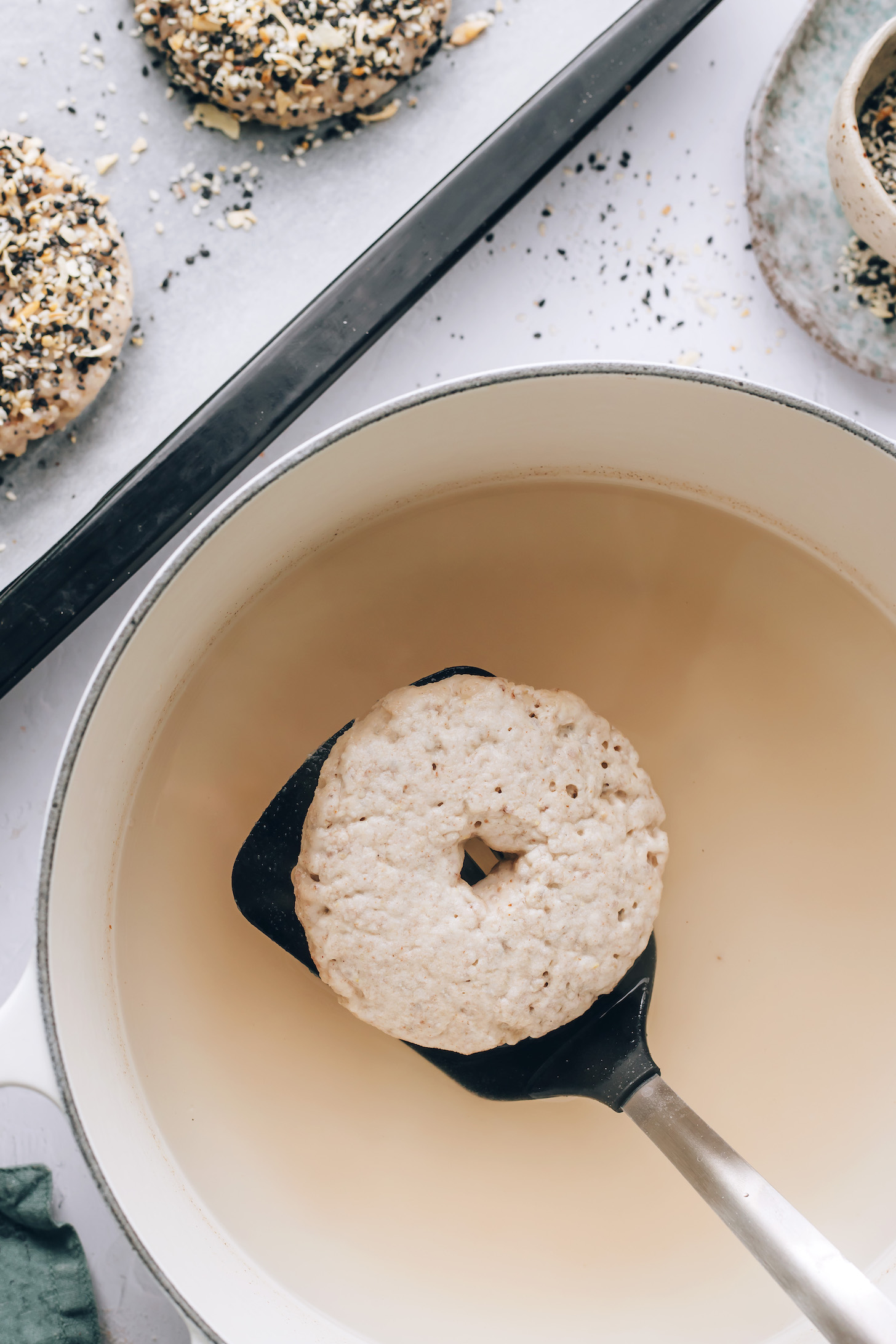 Using a spatula to lift a bagel out of hot water