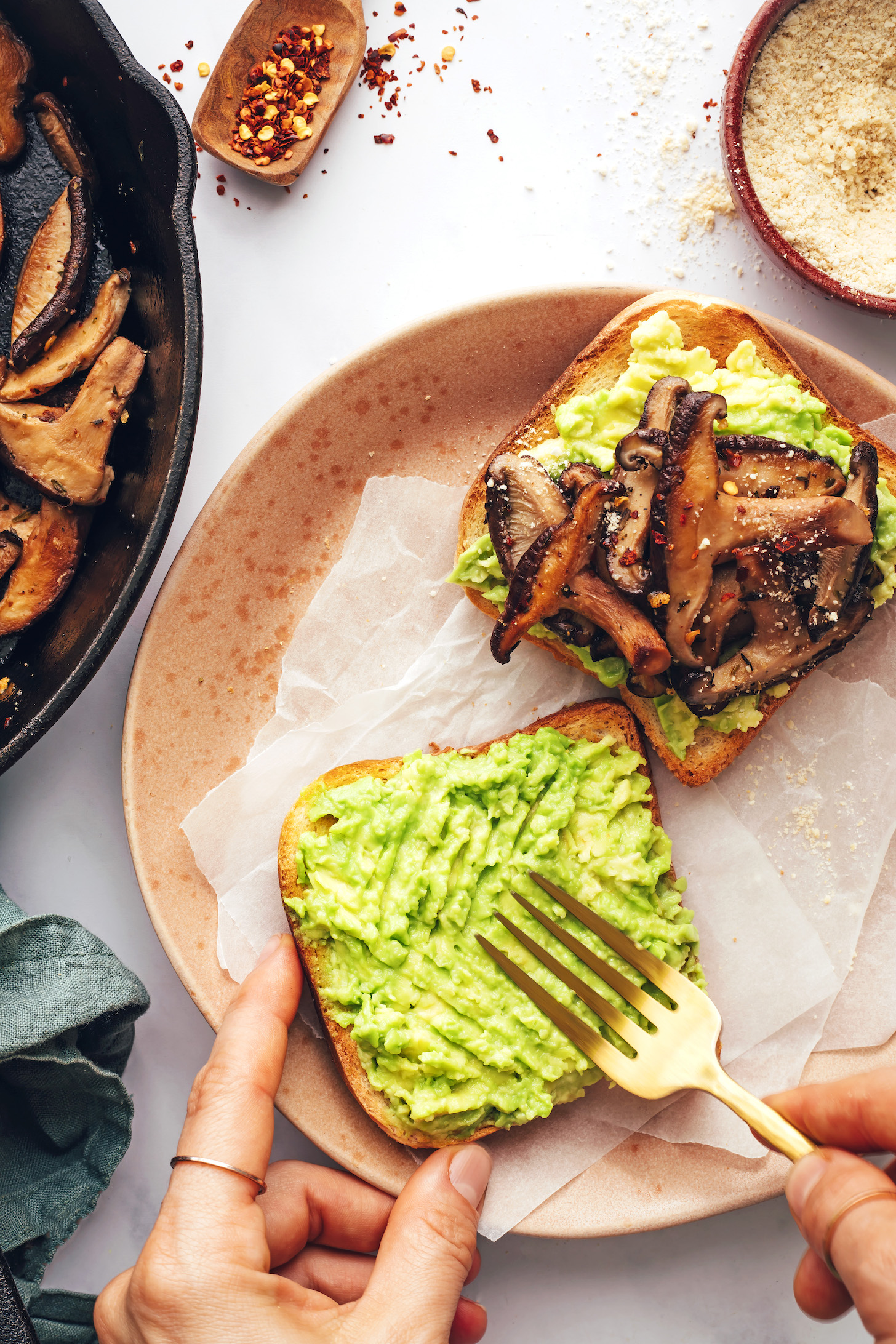 Using a fork to smash ripe avocado onto a slice of toast
