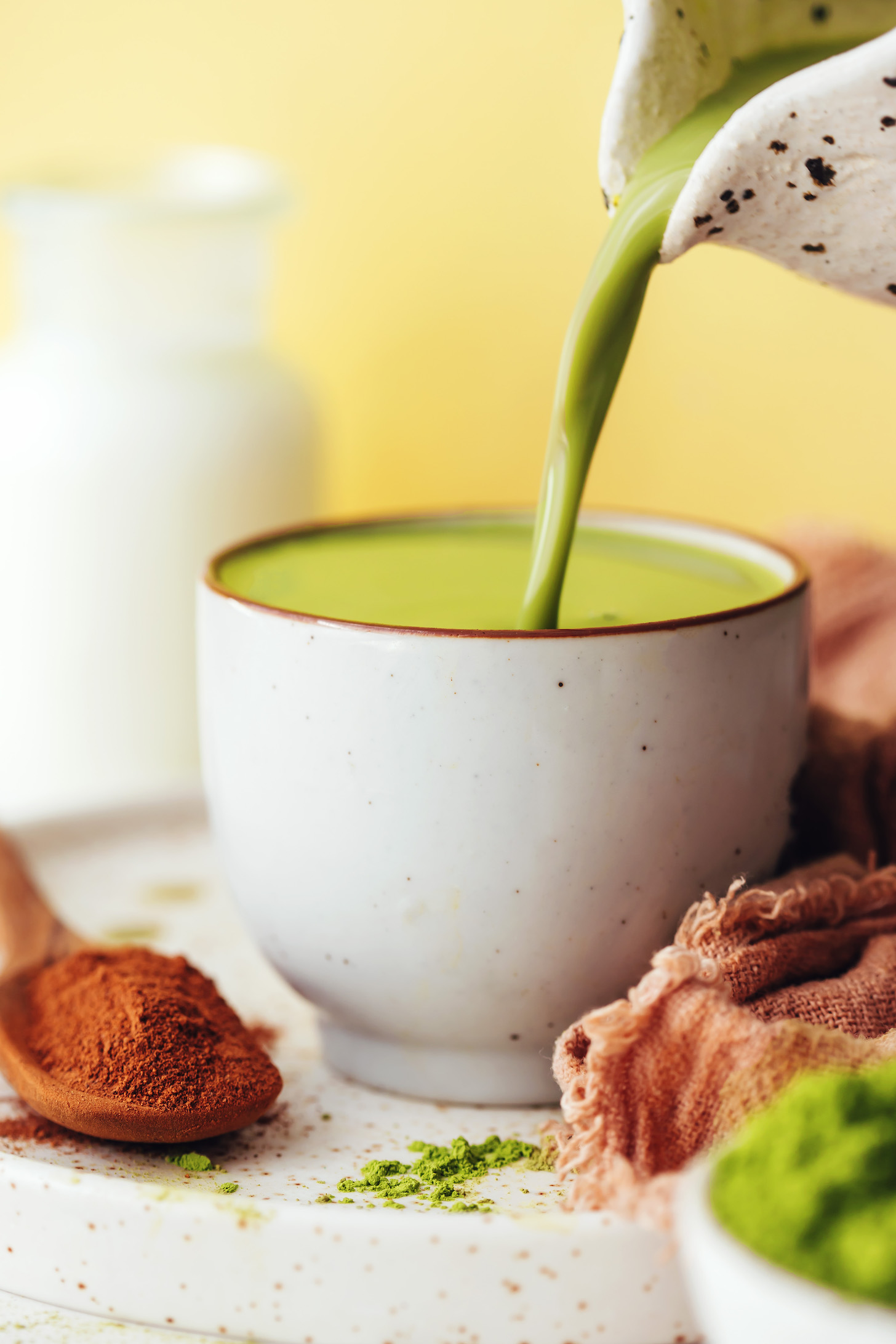 Pouring a pumpkin spice matcha latte into a mug