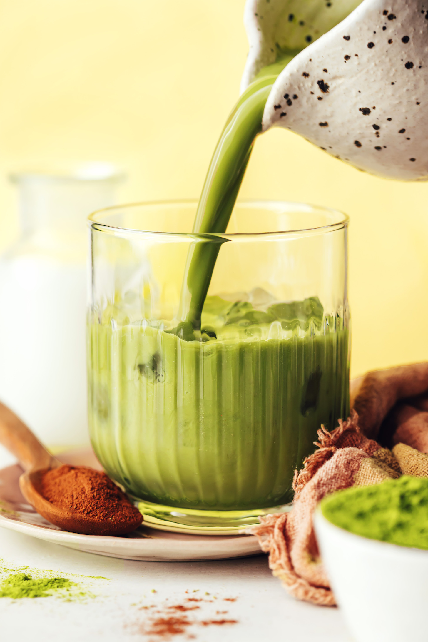 Pouring a matcha latte onto ice in a glass