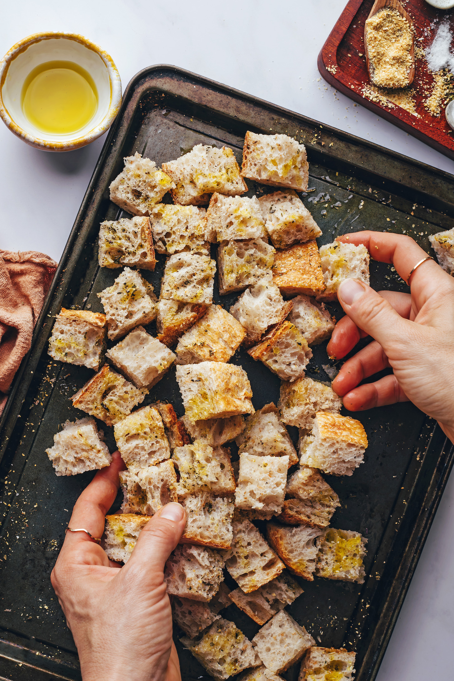 Tossing cubed bread on a baking sheet with oil and seasonings