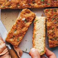 Hand reaching in to pick up a slice of gluten free focaccia bread