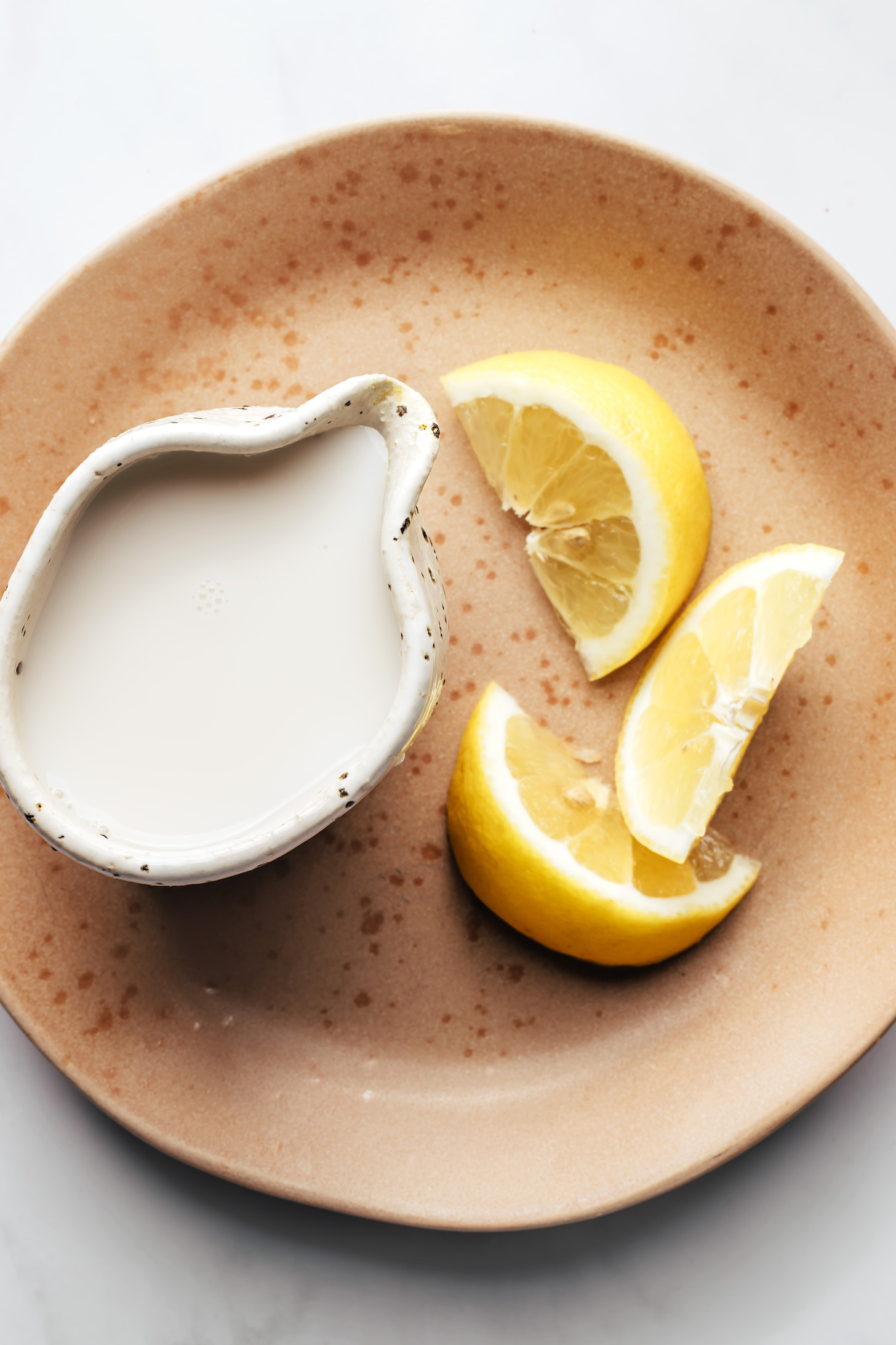 Almond milk and lemon wedges on a plate
