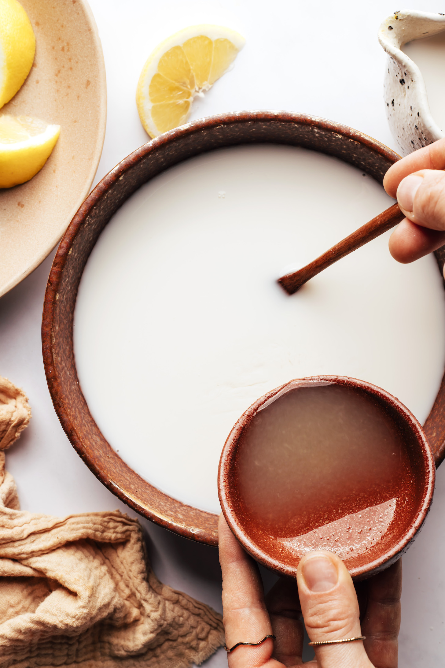 Pouring lemon juice into a bowl of almond milk