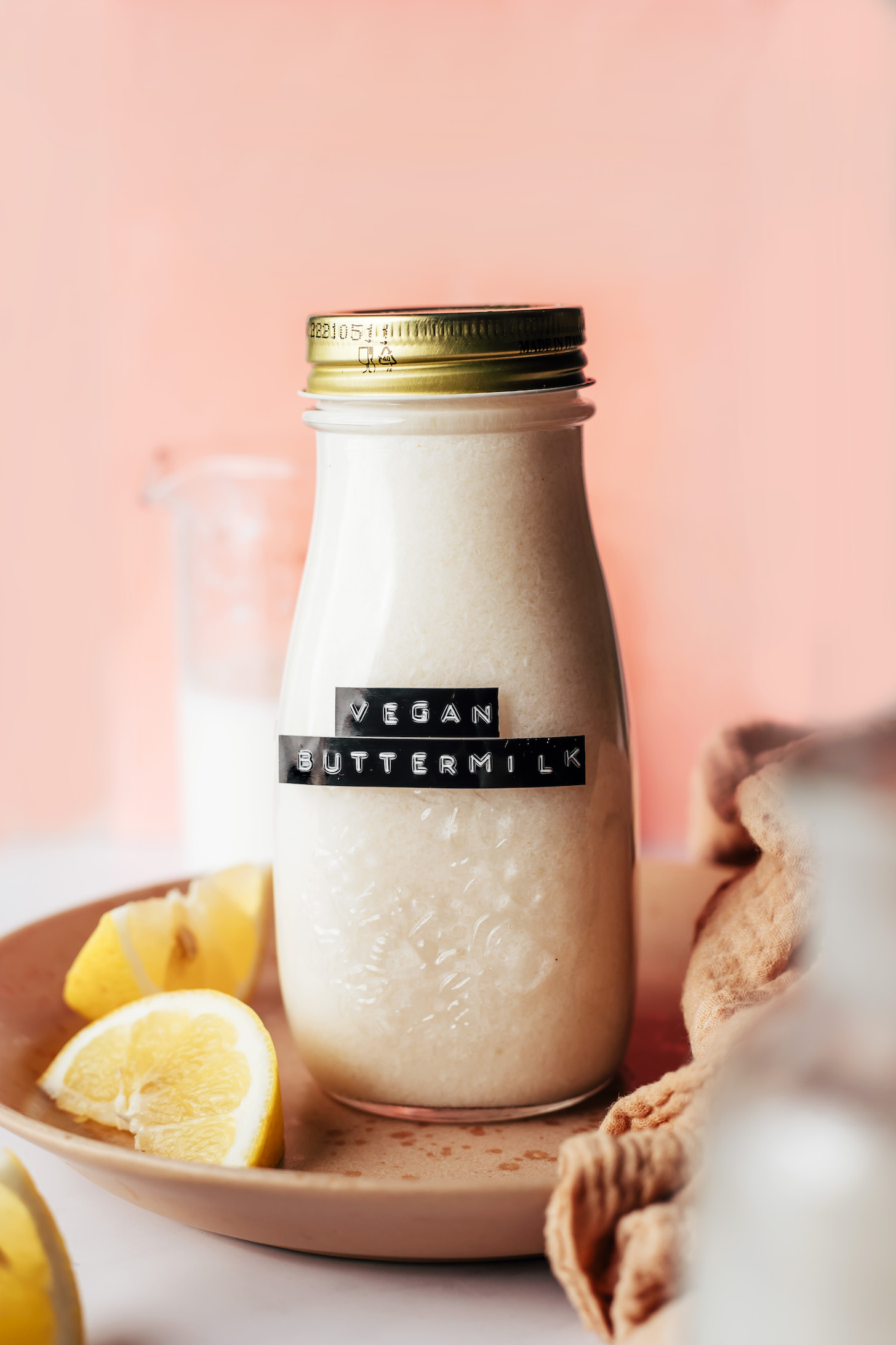 Lemon wedges on a plate with a jar of vegan buttermilk