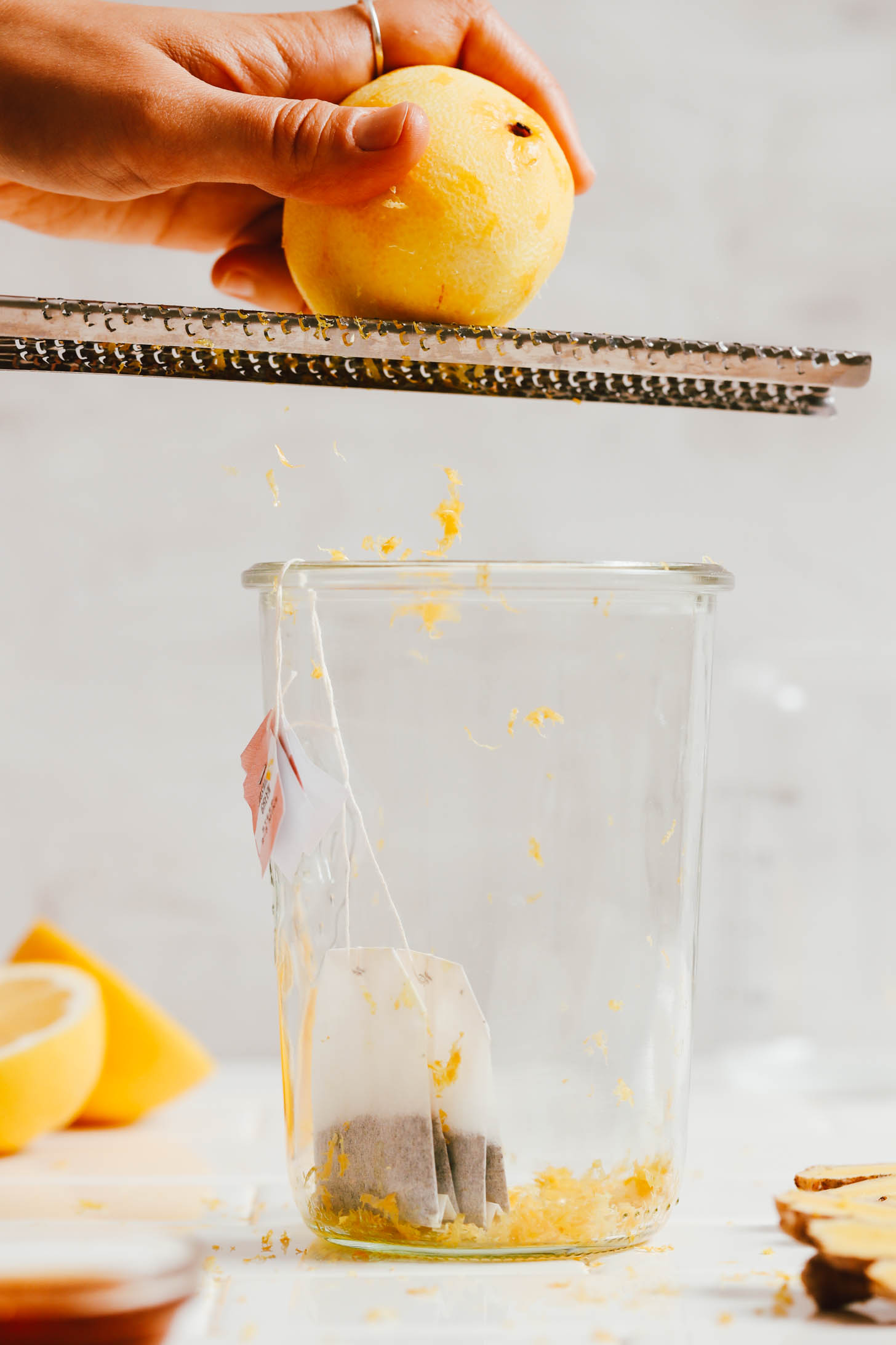 Zesting a lemon over a weck jar with two jasmine green tea bags