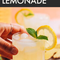 Hand reaching in to pick up a glass of refreshing ginger lemonade