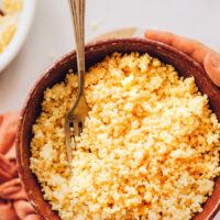 Hands holding a bowl of freshly cooked millet