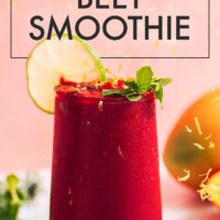 Glass of vegan and gluten-free vibrant mango beet smoothie with a fresh lime slice on the side
