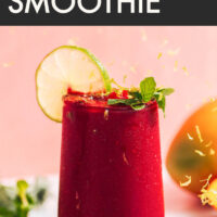 Glass of vegan and gluten-free vibrant mango beet smoothie with a fresh lime slice on the side