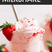 Glass of vegan and gluten-free creamy strawberry milkshake with vegan whipped cream on top